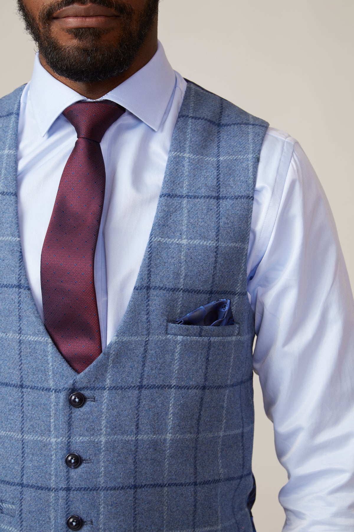 A man wears the marcdarcy CLINTON Blue Tweed Check Waistcoat with a light blue shirt, burgundy tie, and pocket square, shown from shoulders to waist against a neutral background.