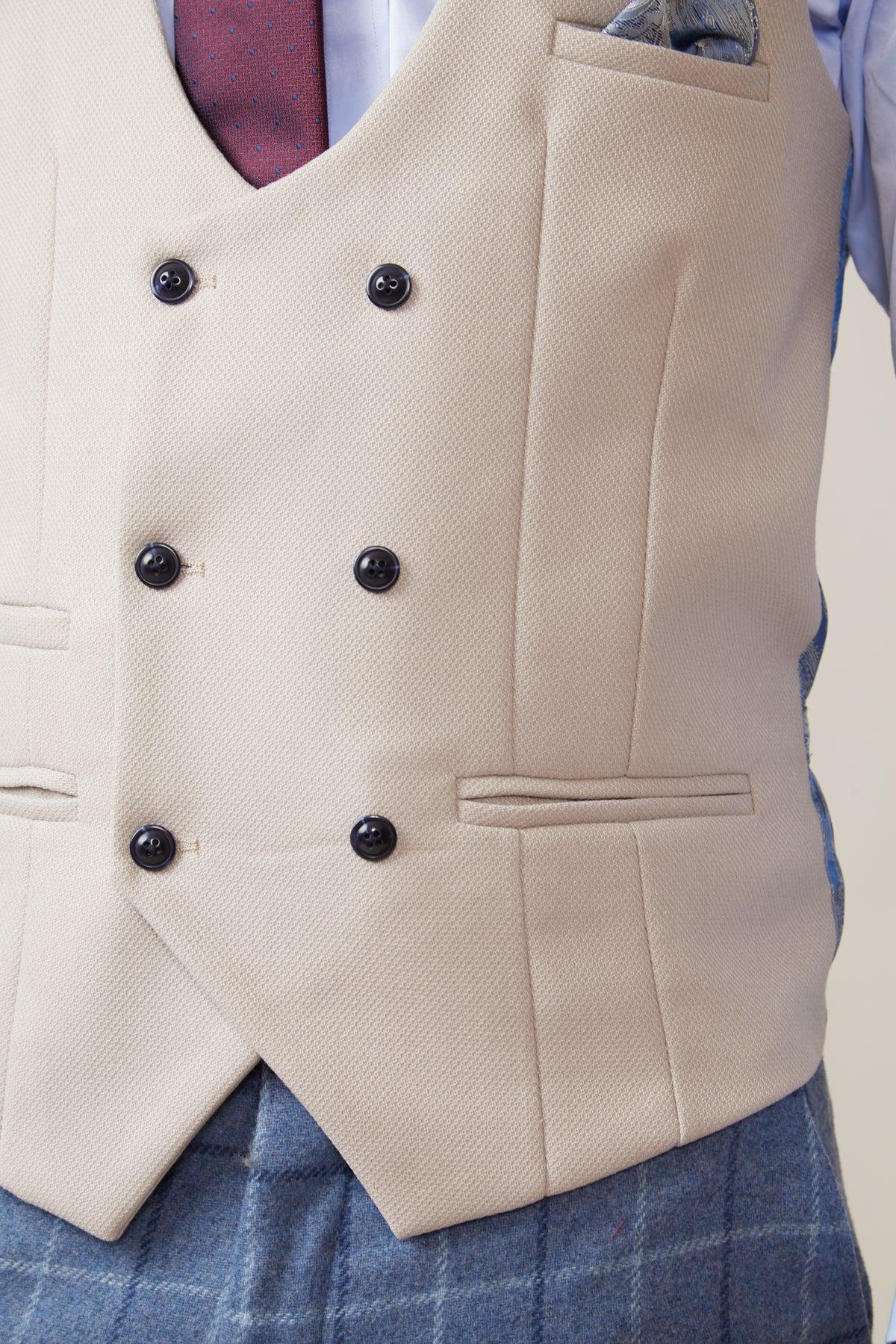 A close-up of a person wearing the marcdarcy KELVIN - Stone Double Breasted Waistcoat with black buttons, styled over a blue checkered suit, burgundy tie, and pocket square in the breast pocket.