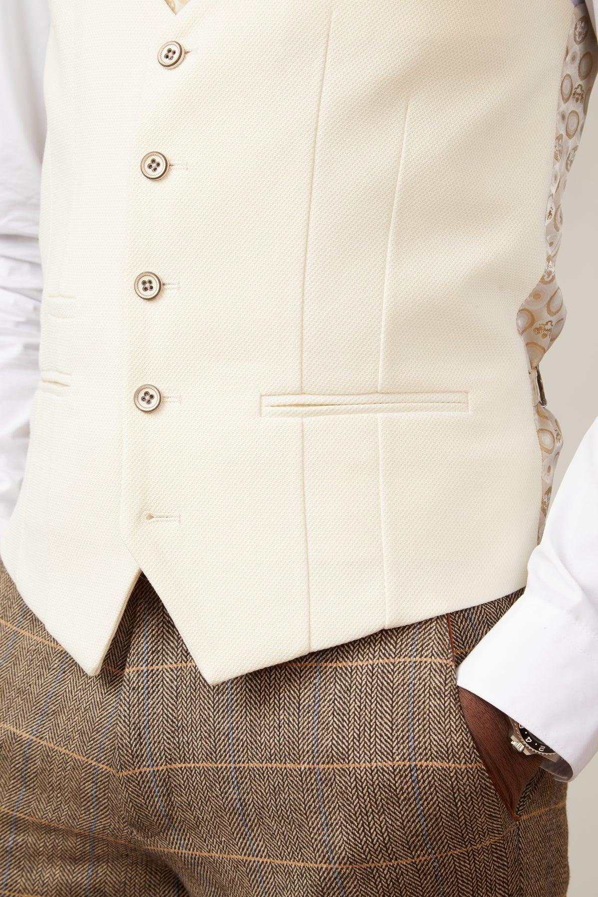A person wears the marcdarcy TED - Tan Tweed Check Suit with a Kelvin Cream Waistcoat, styled over a white shirt—showcasing timeless country elegance. Only their torso and part of the arm with a hand in the pocket are visible.