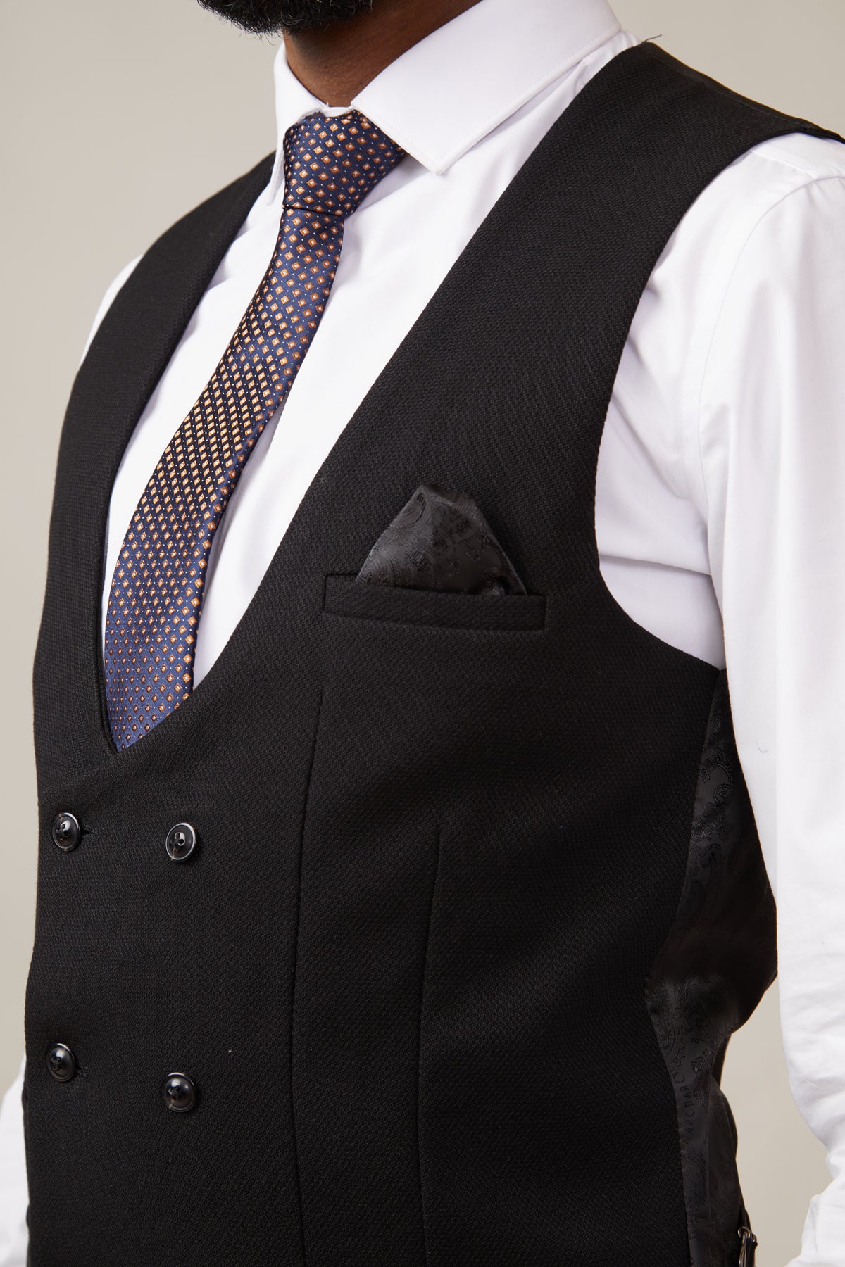 A man wears a white dress shirt, a blue and gold patterned tie, and the marcdarcy KELVIN Black Double Breasted Waistcoat with a black pocket square.