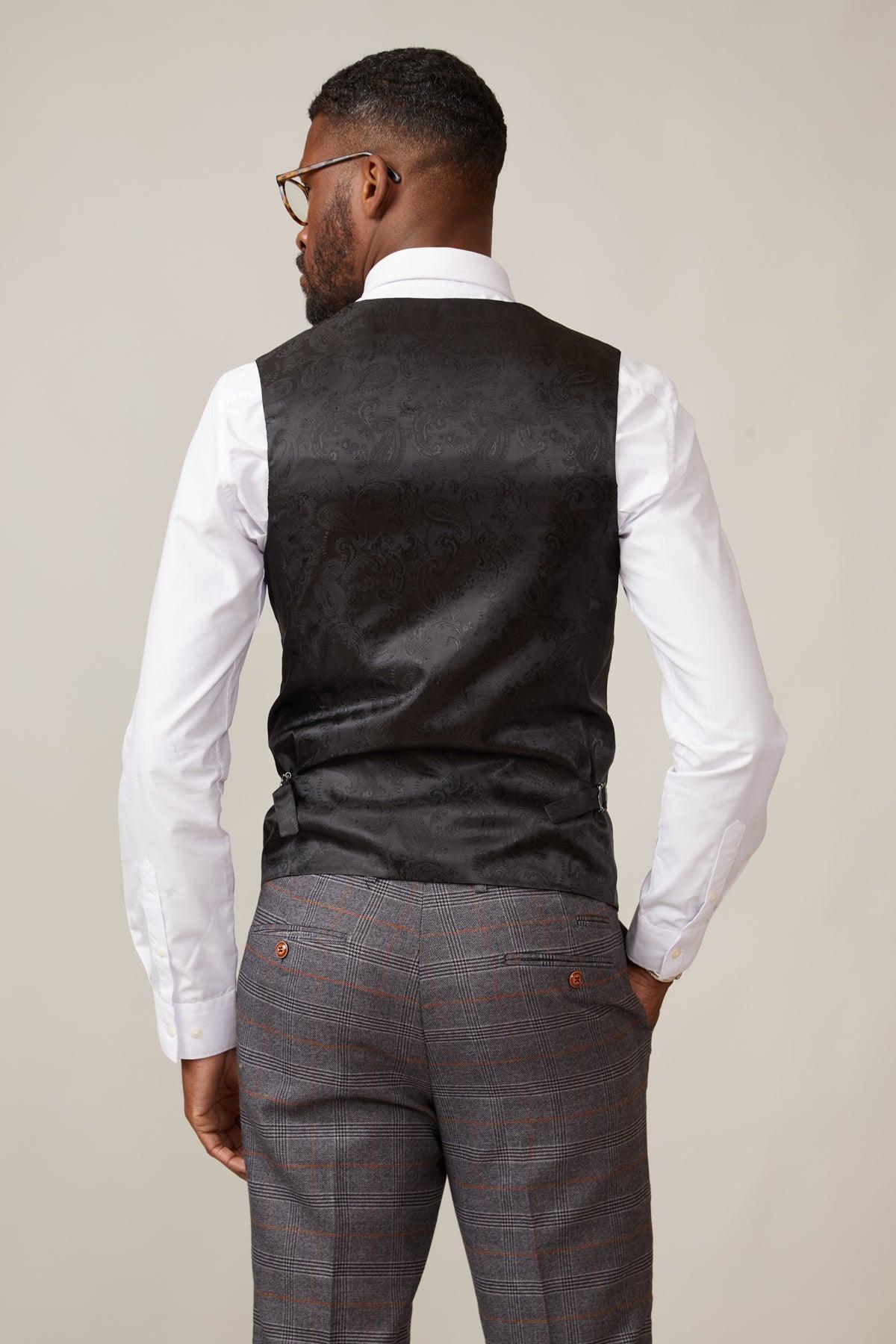 Back view of a Black man in a white shirt, grey plaid trousers, and the marcdarcy KELVIN Black Single Breasted Waistcoat with paisley lining. He wears glasses and has a beard.