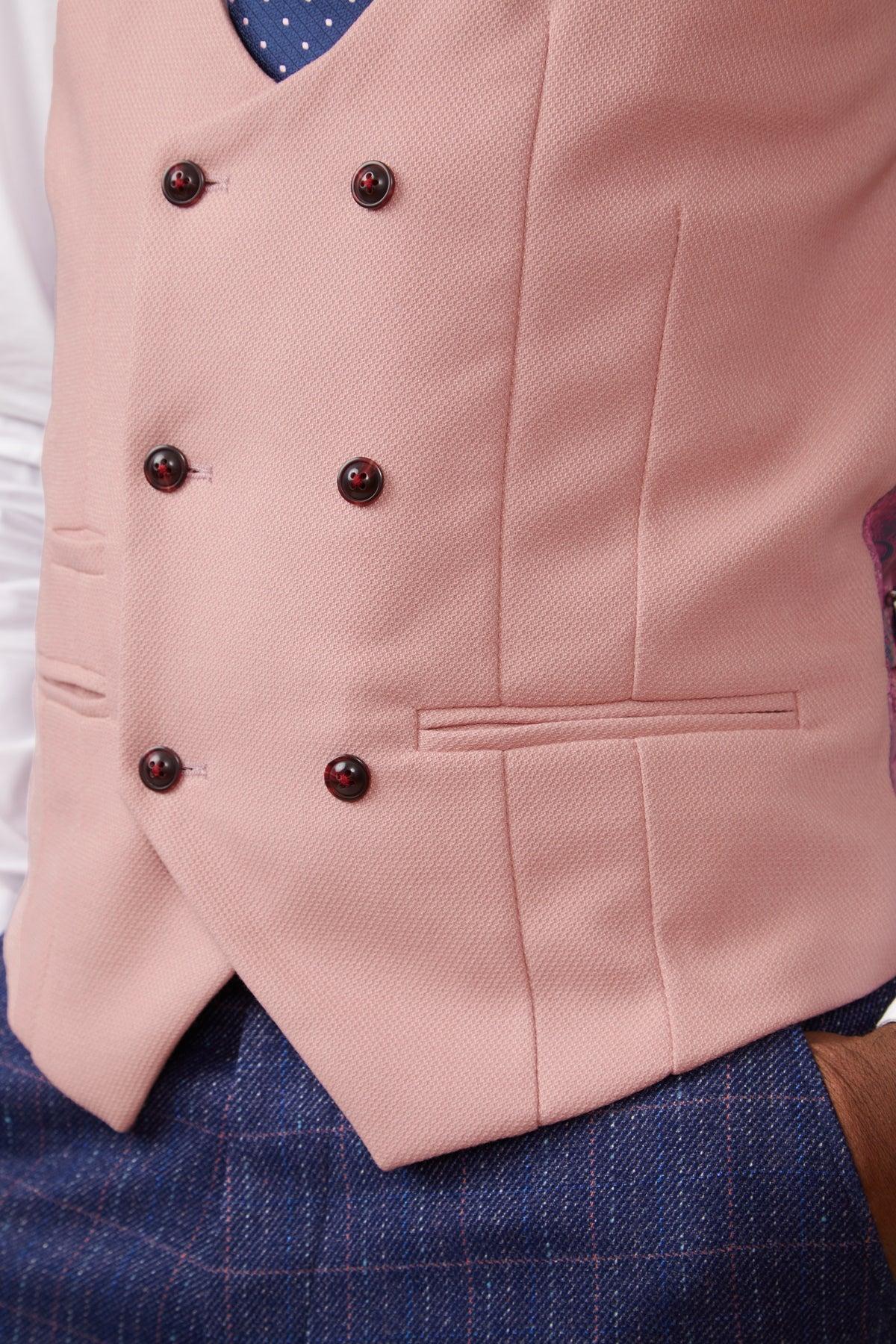 A close-up of a person wearing the marcdarcy KELVIN Pink Double Breasted Waistcoat with dark buttons, paired with a white shirt, navy patterned tie, and blue plaid pants.