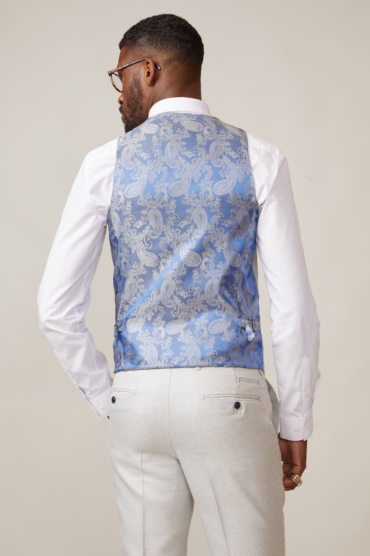 Back view of a man in a slim fit penny collar shirt, marcdarcy RONALD Stone Single Breasted Waistcoat, and light gray slacks.