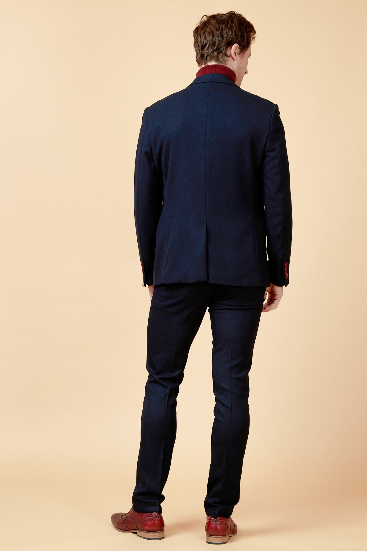 A man faces away from the camera, wearing the marcdarcy JD4 - Navy Contrast Trim Two Piece Suit with brown shoes, set against a plain beige background.