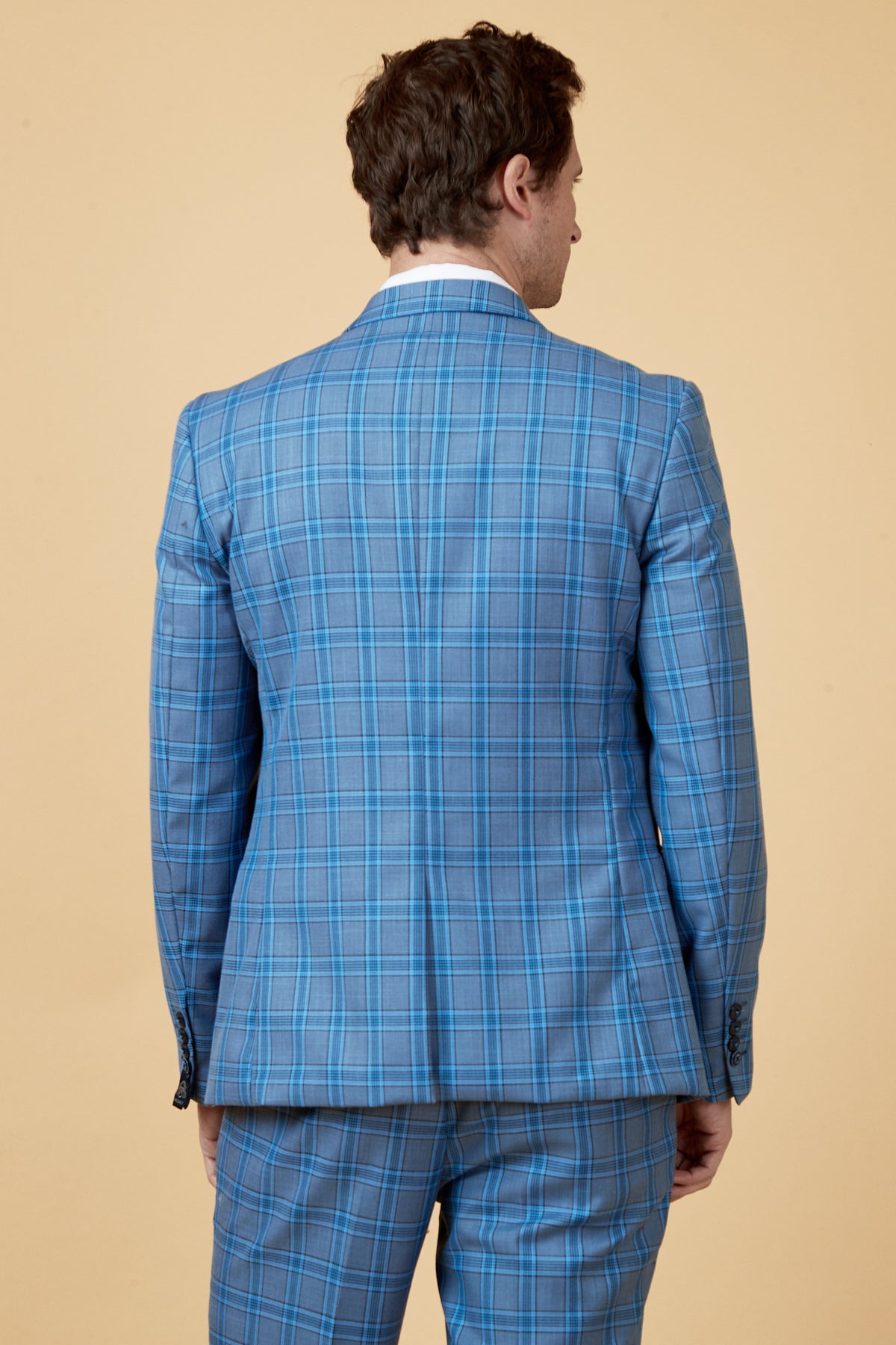 A man stands with his back to the camera against a beige background, wearing the JOSE - Sky Blue Check Blazer by Marc Darcy, paired with matching tailored fit pants.