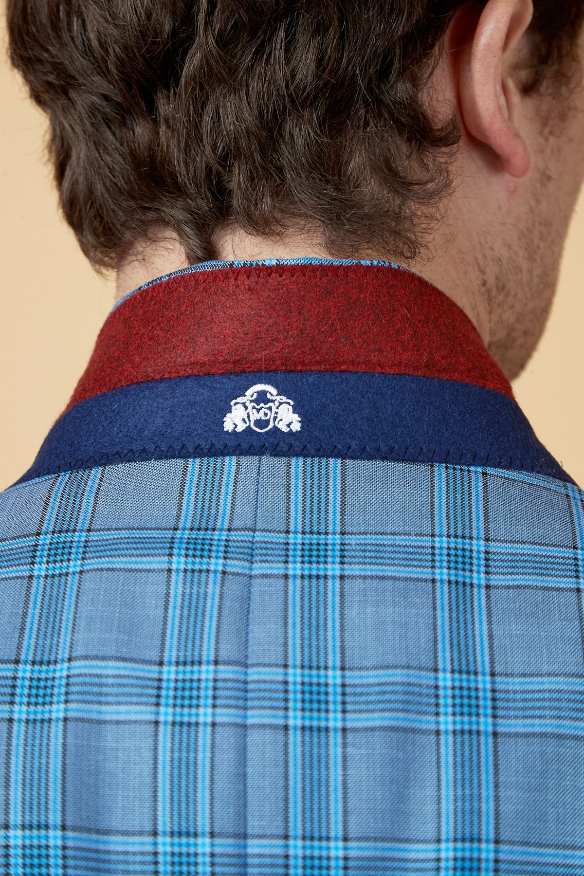 Close-up of a man's back and neck wearing the marcdarcy JOSE Sky Blue Check Two Piece Suit, featuring a maroon collar and a dark blue band with a white embroidered logo.
