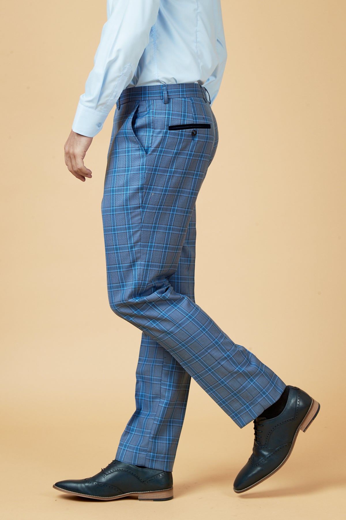 A person wearing the marcdarcy JOSE Sky Blue Check Three Piece Suit and black dress shoes stands against a beige background, shown from the side.