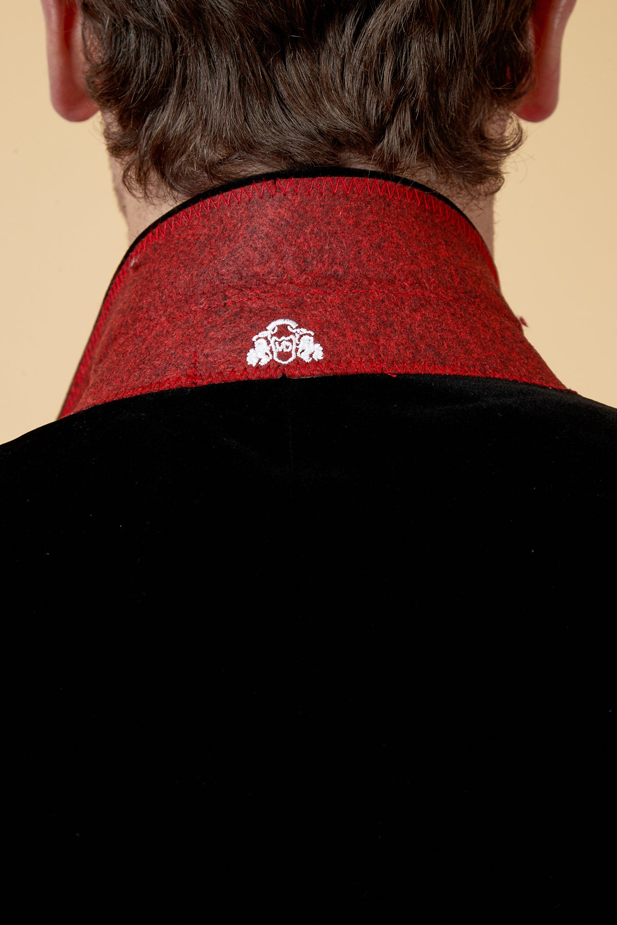 Close up of the back of a man's neck in the marcdarcy HUDSON Black Velvet Blazer, featuring a tailored fit, red felt collar, and white embroidered crest—ideal for a sophisticated black tie look.