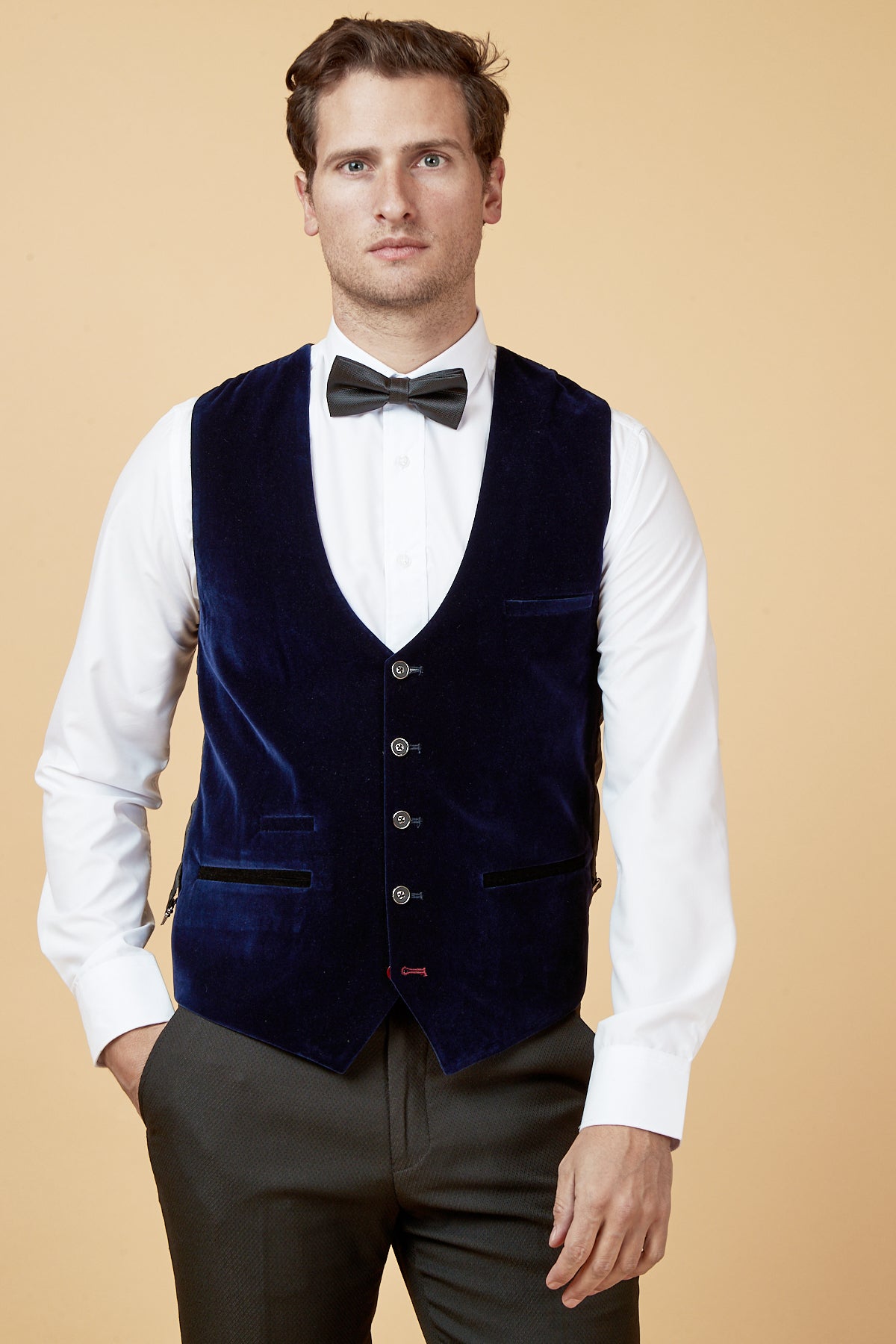 A man wears the marcdarcy HUDSON Navy Velvet Jacquard Waistcoat over a white shirt and black bow tie, paired with dark trousers.