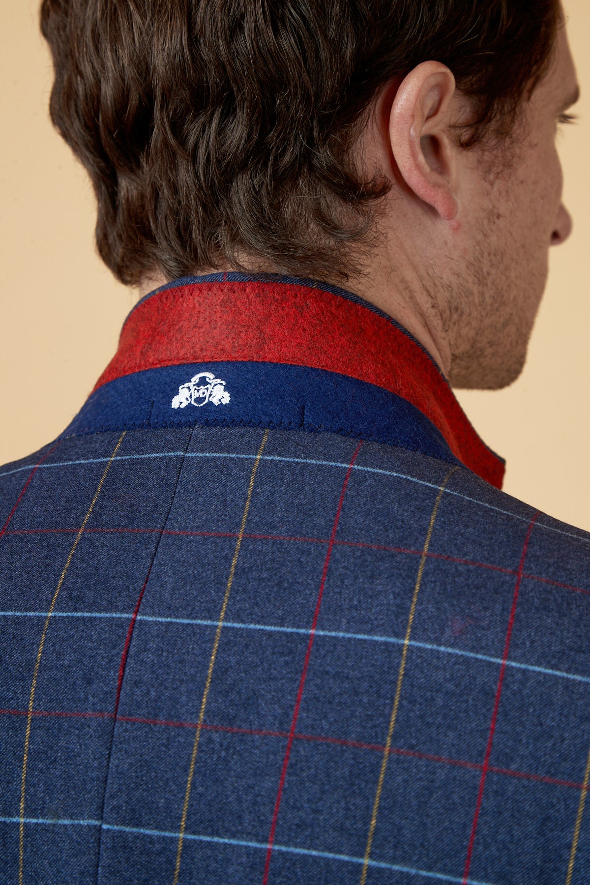 A close-up of a man's back highlights the marcdarcy DRAKE Navy Check Three Piece Suit, featuring bold red and yellow check patterns, a red and navy collar, and a small white embroidered crest at the back of the neck.