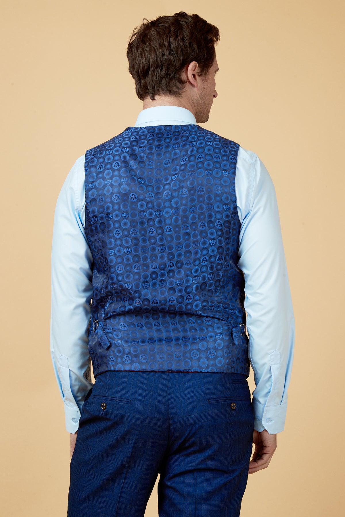 Back view of a man wearing a light blue dress shirt, marcdarcy's LEE GEORGE Royal Blue Double Breasted Waistcoat, and blue plaid trousers—ideal for refined formalwear.