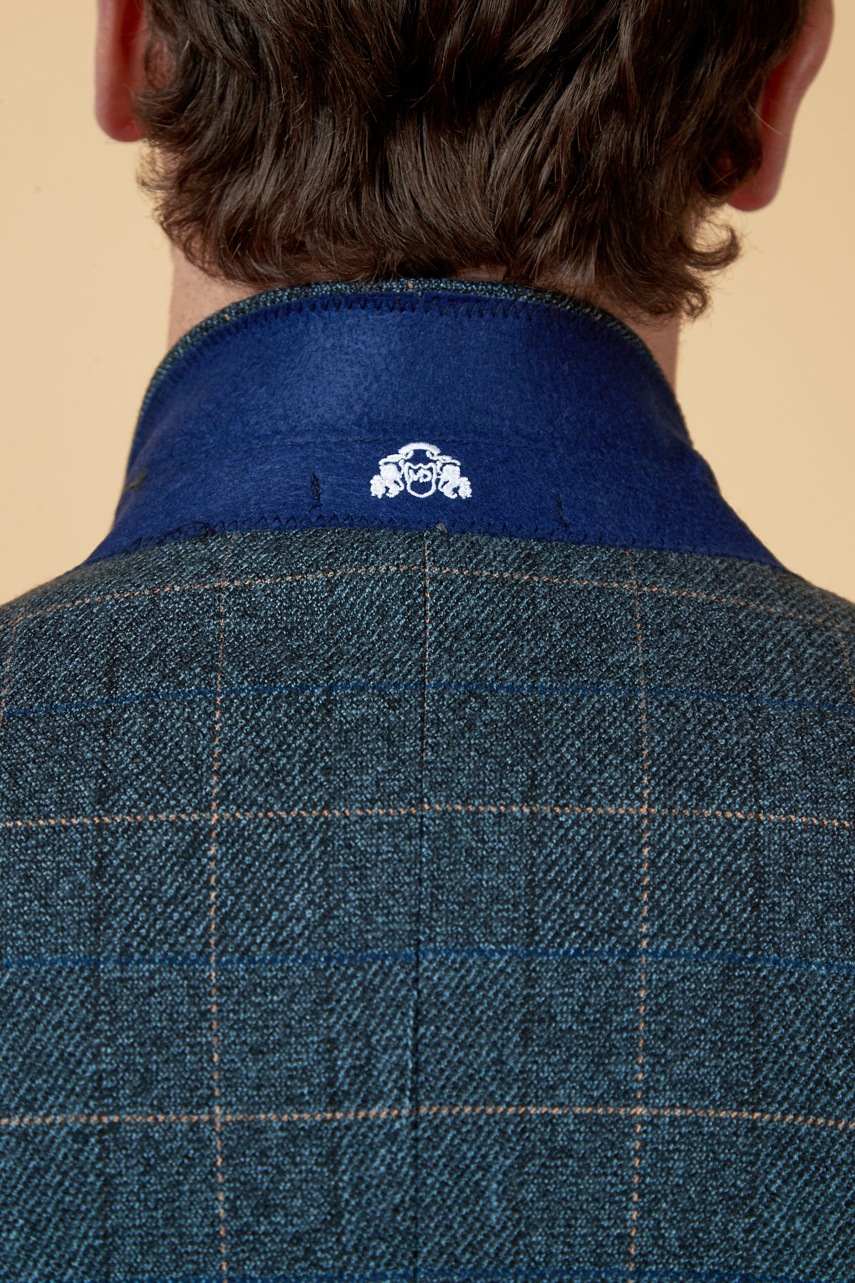 The back view shows brown hair above the collar of a marcdarcy SCOTT - Blue Tweed Check Blazer, featuring green plaid with a blue collar and a small white crest logo inside.