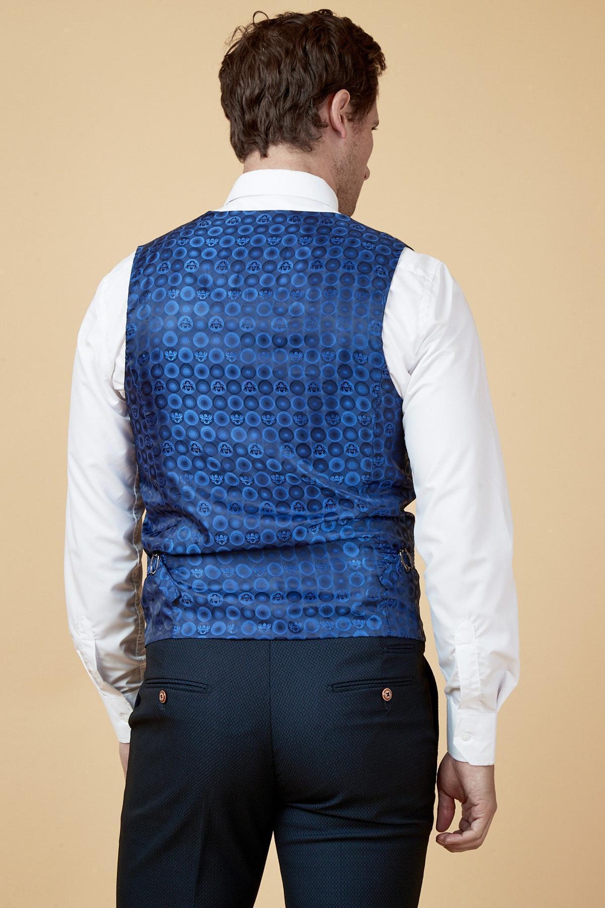 A man is seen from behind wearing the marcdarcy MAX navy single breasted waistcoat over a white dress shirt with dark trousers, set against a plain beige background.