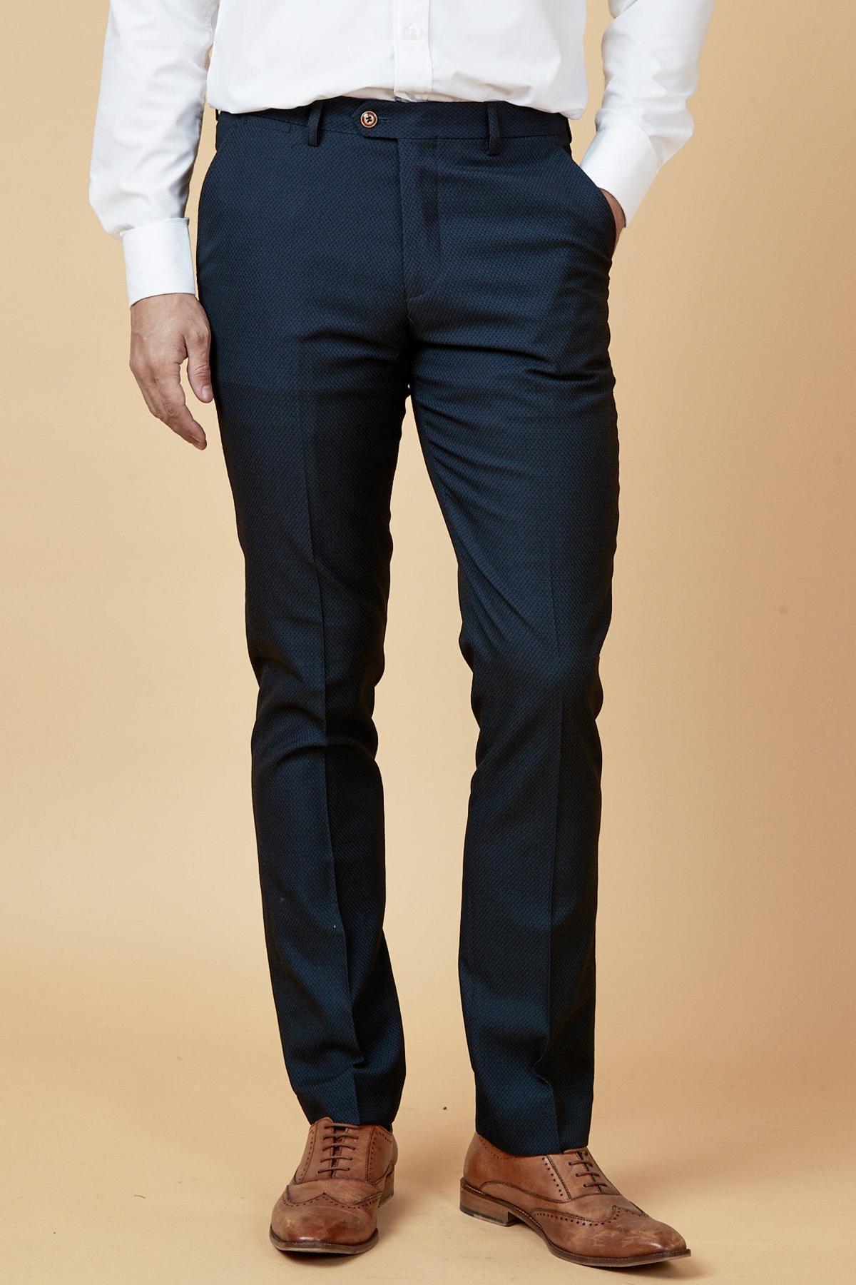 A person wearing a white dress shirt, marcdarcy MAX Navy Blue Trousers with Contrast Buttons, and brown leather shoes stands against a beige background with one hand in their pocket.
