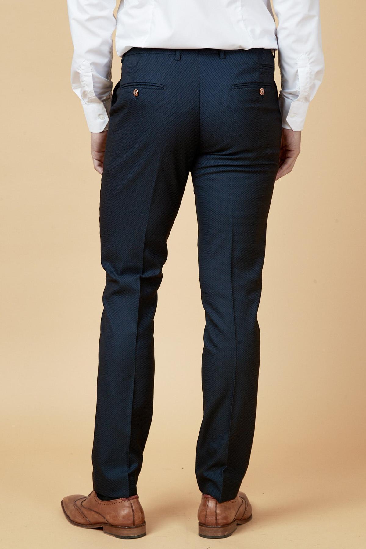 A person stands with their back to the camera against a beige background, wearing a white dress shirt, marcdarcys MAX Navy Blue Trousers with Contrast Buttons, and brown dress shoes—classic inspiration for refined workwear.