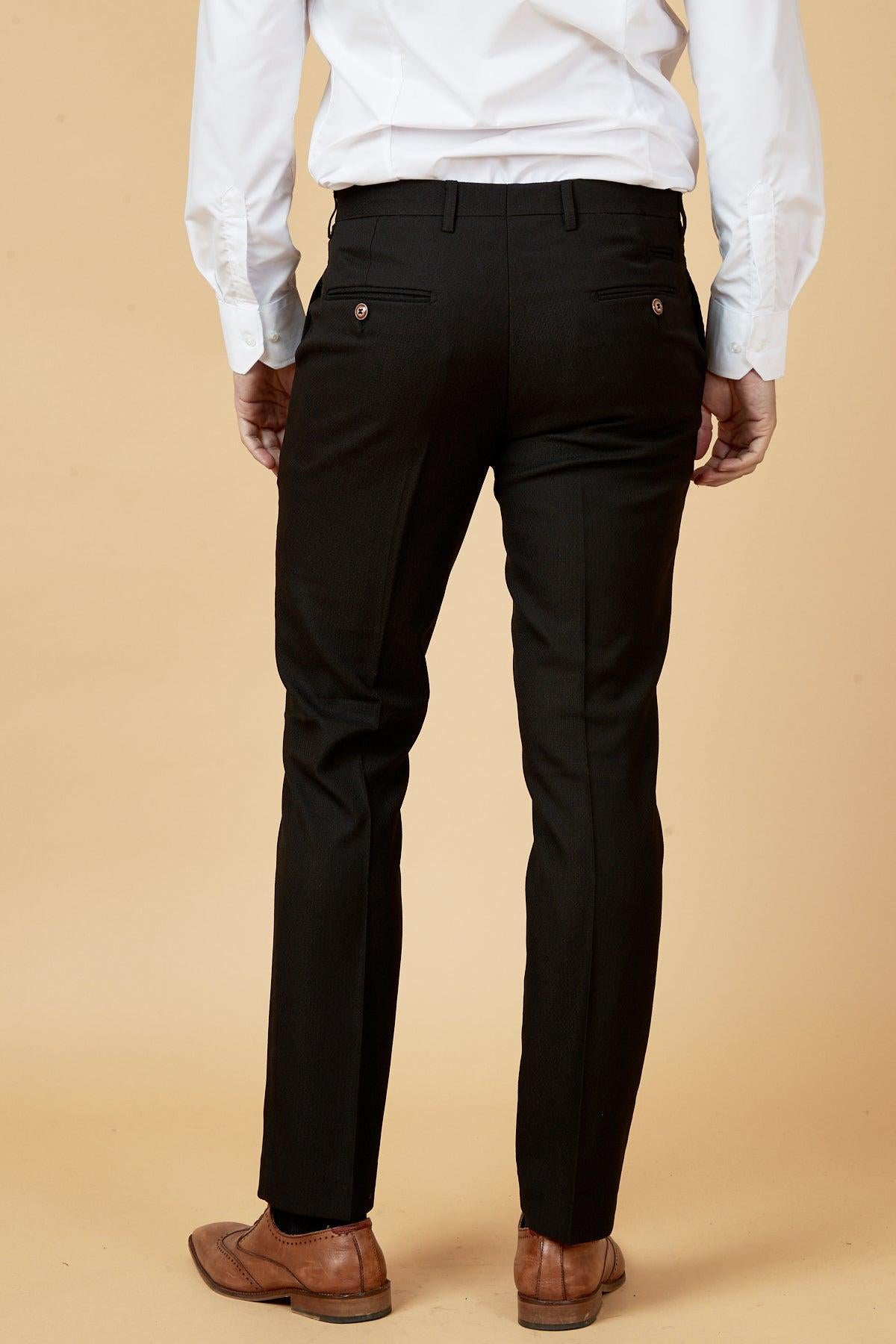 Back view of a man wearing marcdarcy's MAX - Black Trousers with Contrast Buttons, paired with a white dress shirt and brown shoes against a beige background—modern workwear at its best.