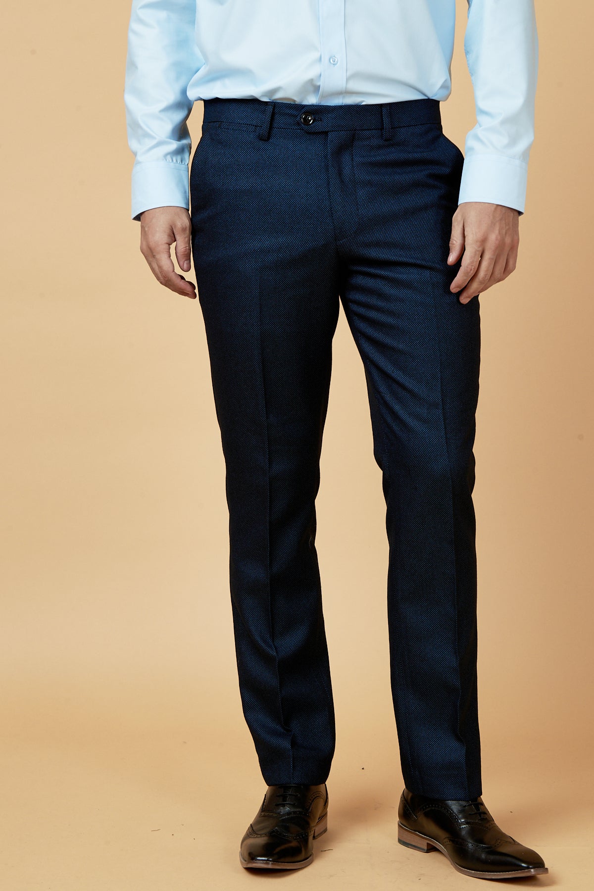 Wearing the marcdarcy CALLUM - Blue Three Piece Suit, a person stands against a beige background. The formal ensemble, tailored in blue, is shown from shoulders to feet for a complete look.