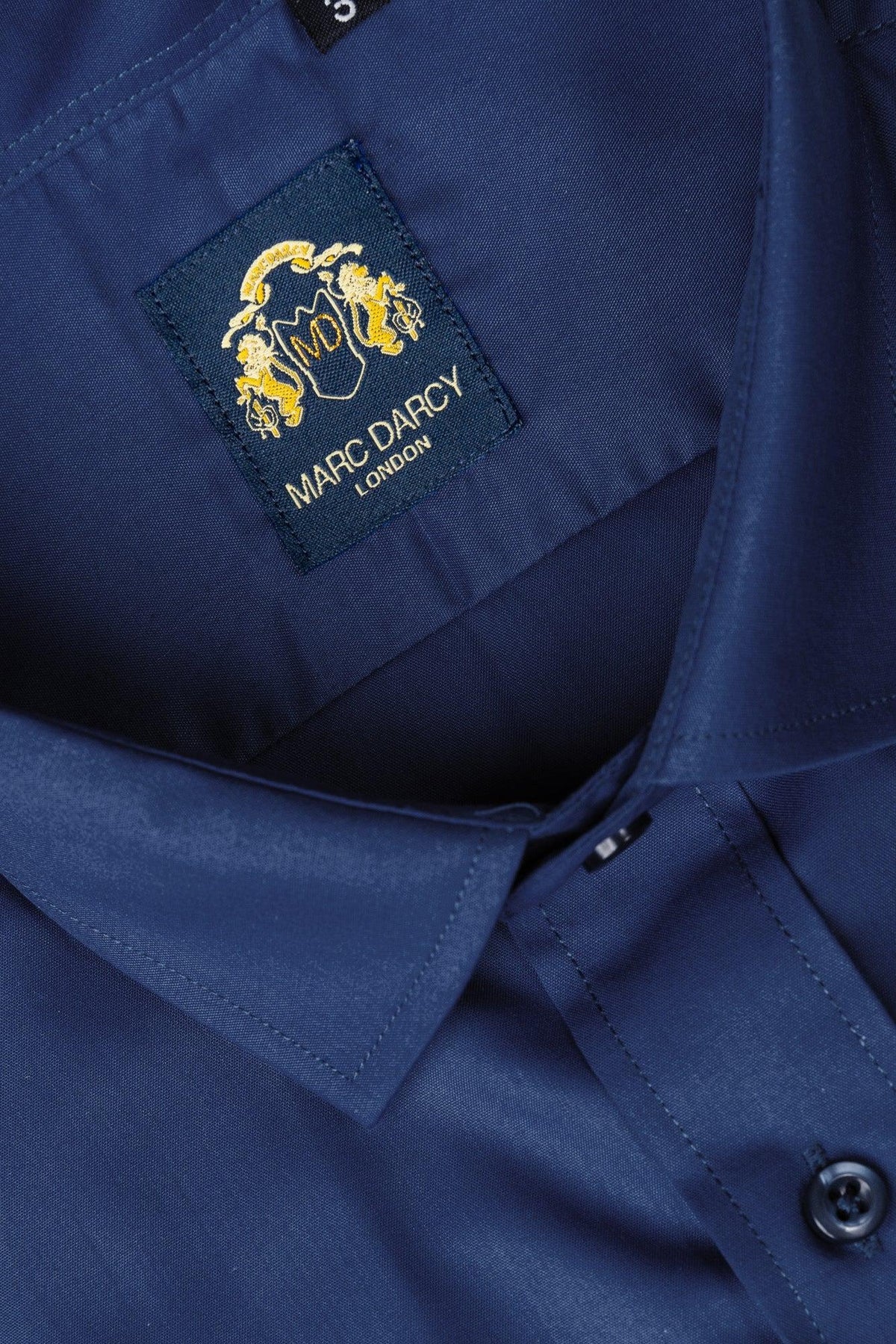 Close-up of the CARTER - Blue Long Sleeve Shirt by Marc Darcy, featuring a spread collar and an inner label displaying the Marc Darcy name with a gold crest design above the text.