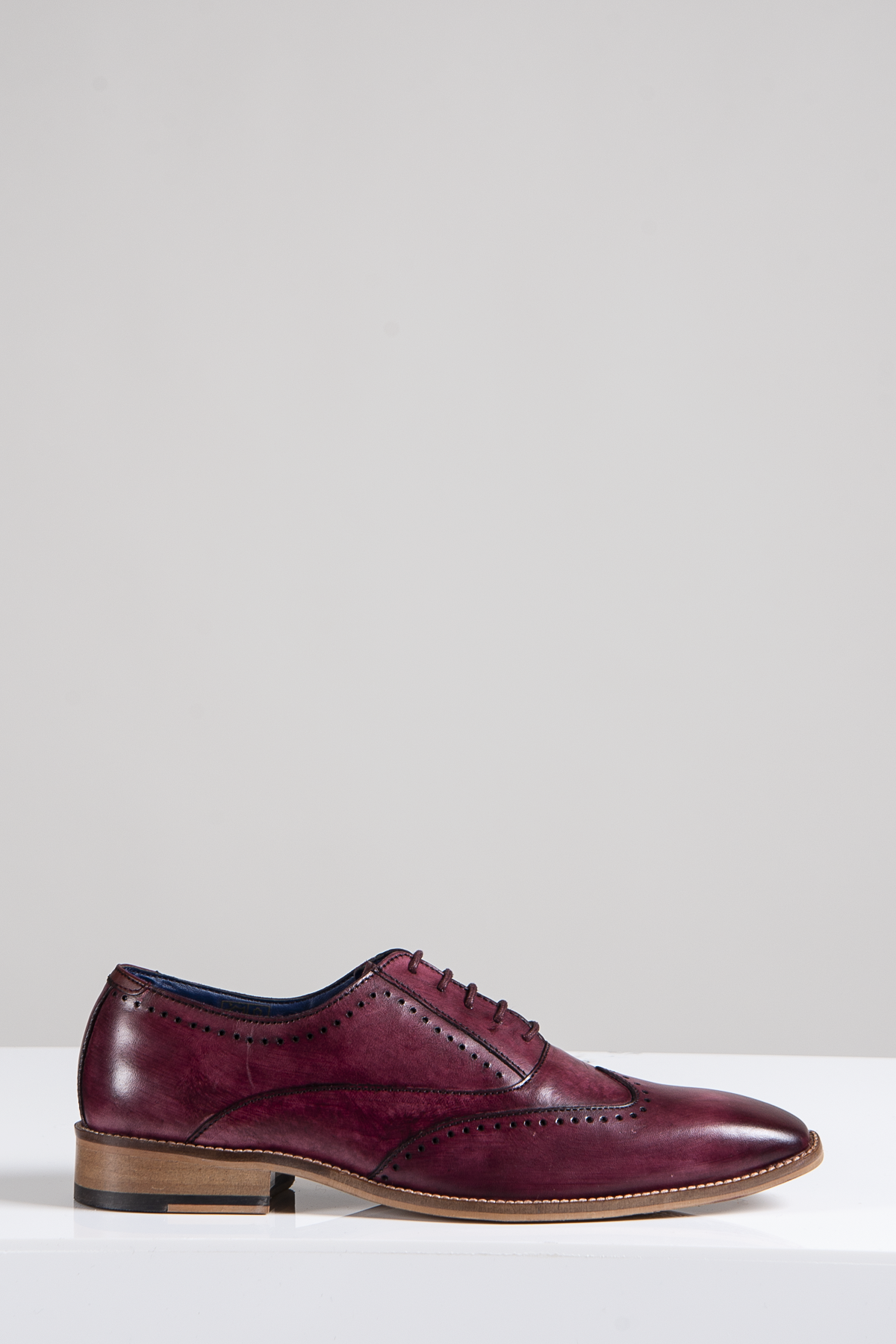 The Marc Darcy CARSON - Bordeaux Burgundy Wingtip Oxford Brogue Shoe, crafted from full grain leather with brogue detailing and a stacked wooden heel, is displayed against a light gray background.