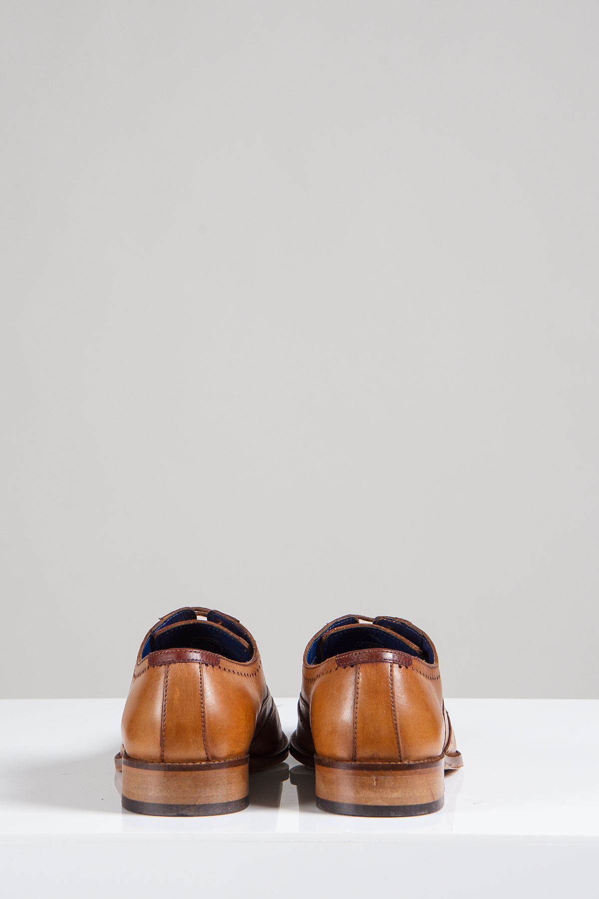 The CARSON Mid Tan Wingtip Oxford Brogue Shoes by Marc Darcy are shown from the back, placed on a white surface against a plain light gray background.