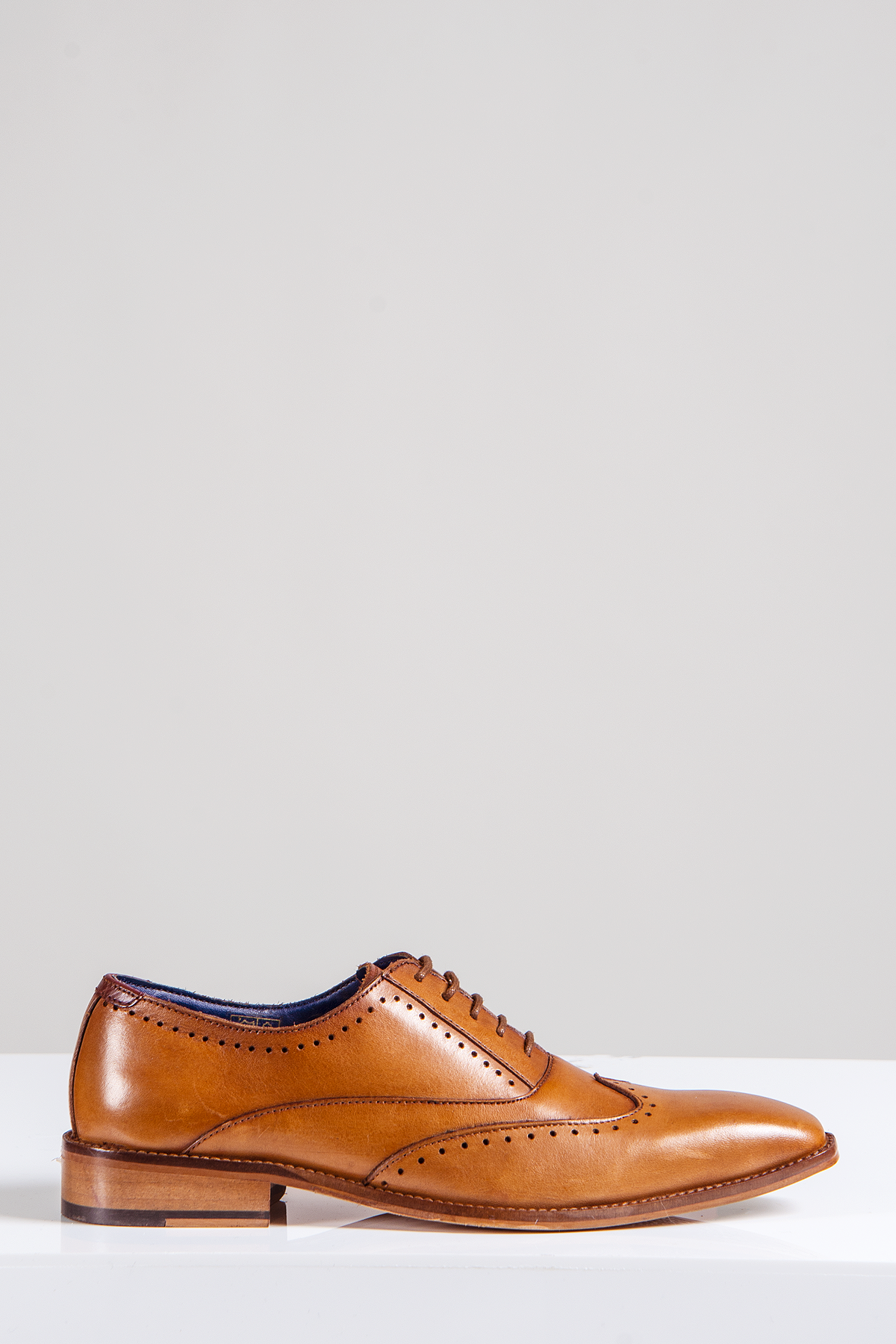 The Marc Darcy CARSON Mid Tan Wingtip Oxford Brogue Shoe, crafted from full grain leather with brogue detailing, closed lacing, and a wooden sole, is shown on a white surface against a light gray background.