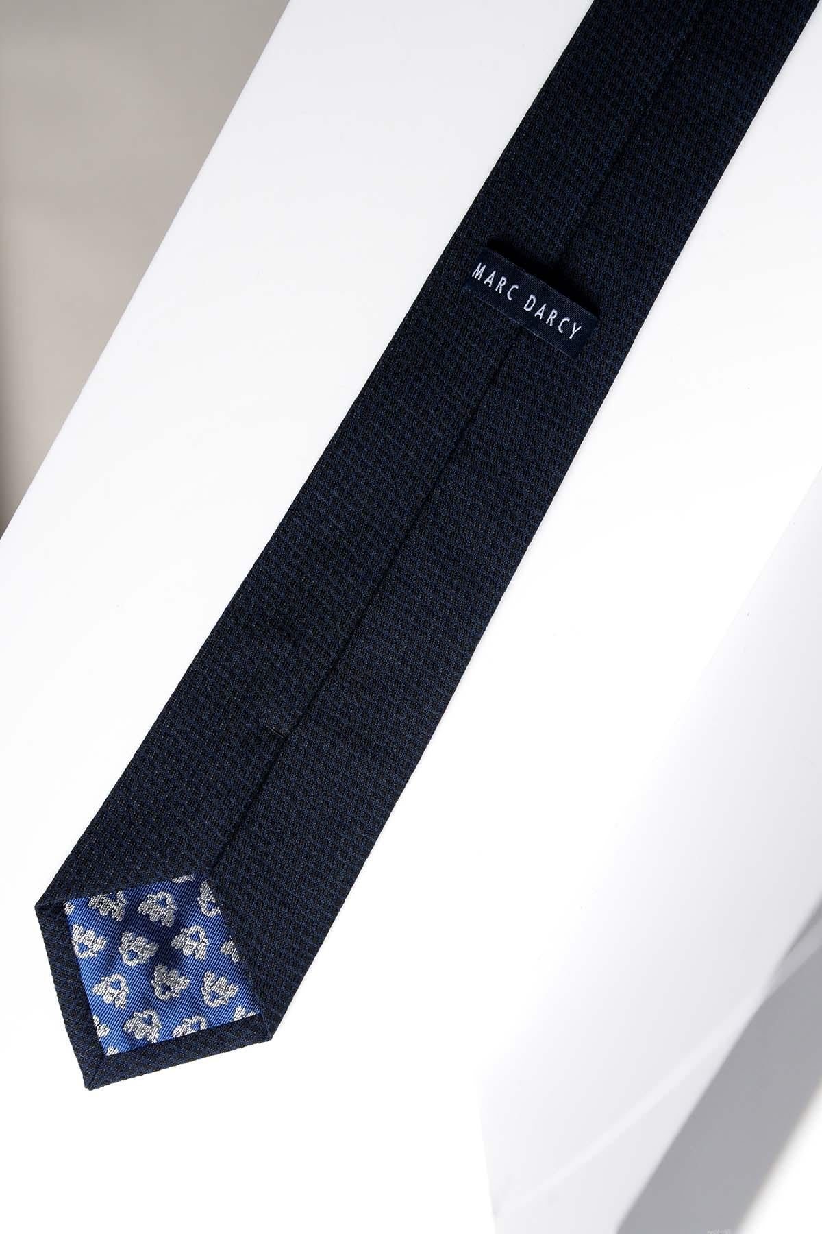 The MAX Navy Diamond Print Tie by Accessory is ideal for formalwear or weddings. This dark blue tie features a diamond pattern, blue lining with light grey floral details at the inner tip, and is shown on a white surface.