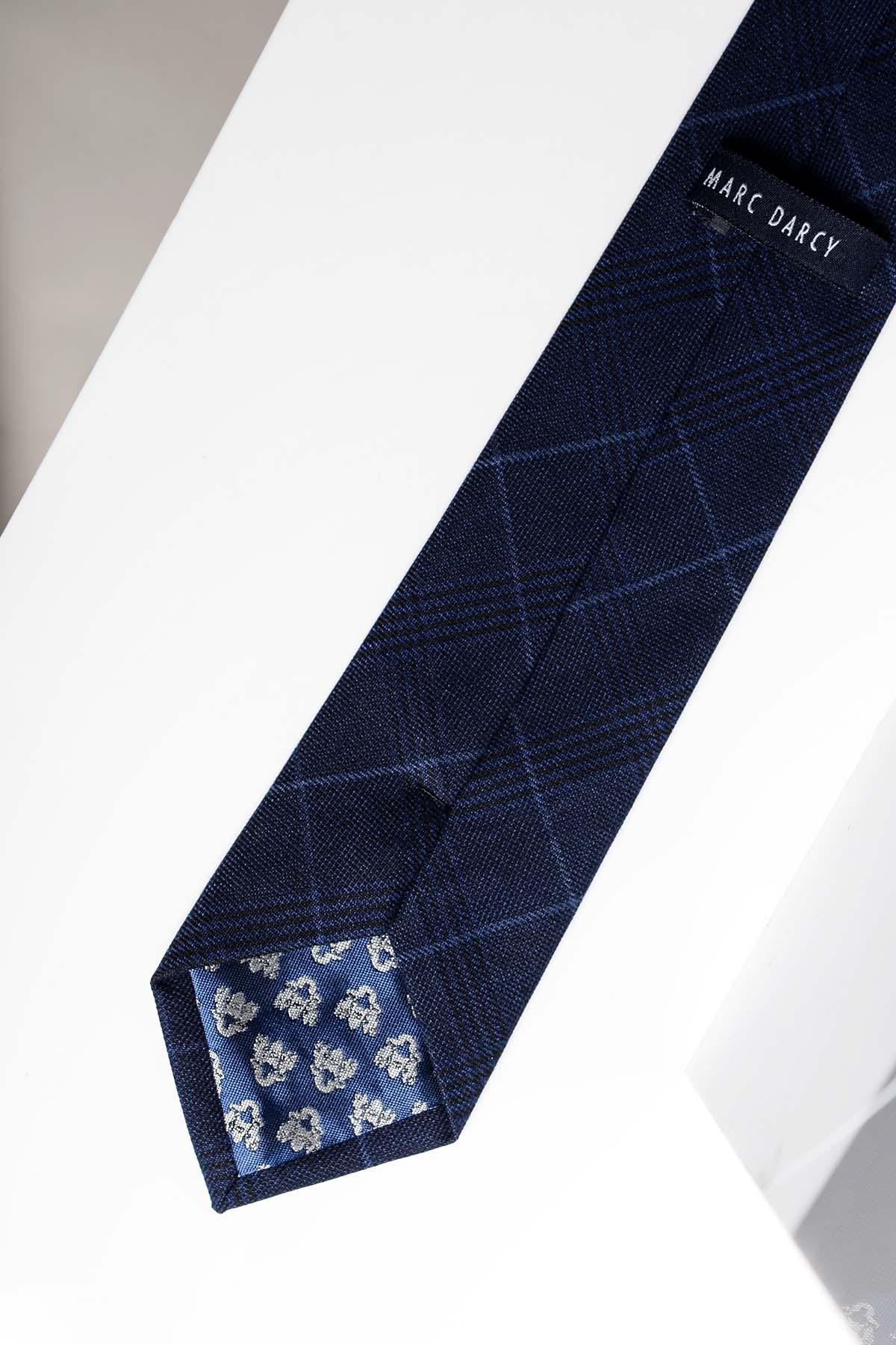 The EDINSON - Navy Sky Check Tie by Accessory is a men's formal tie with a subtle check pattern and a floral print on the inner tip, featuring the brand label on the underside, elegantly displayed on a white surface.