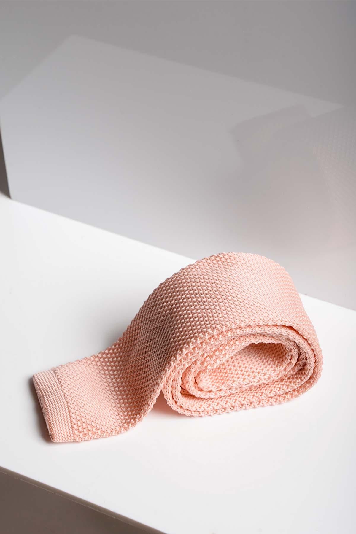The KT - Peach Knitted Tie by Accessory is rolled up on a white surface with a modern, minimal background—perfect for spring and summer looks or as a stylish wedding accessory.
