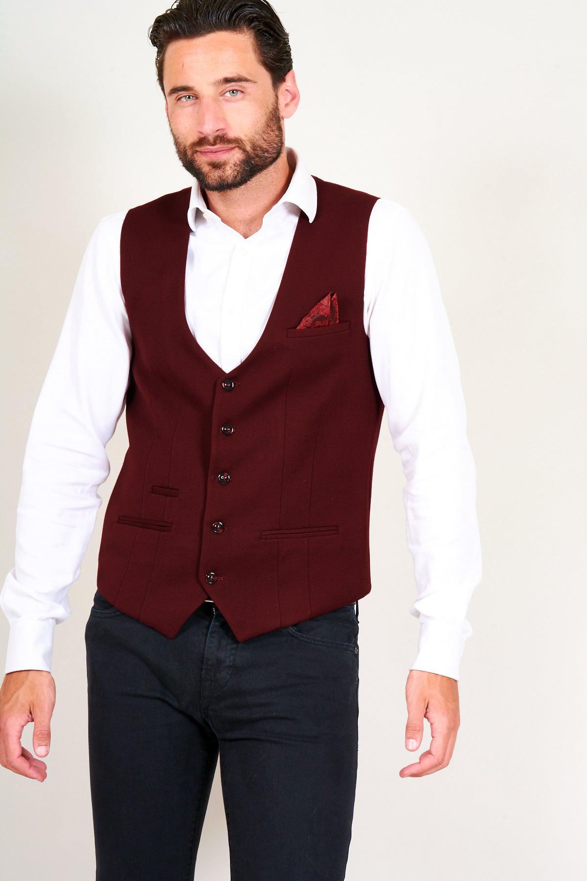 A man wears the marcdarcy KELLY - Wine Single Breasted Waistcoat over a white shirt and dark jeans, styled with a patterned pocket square.