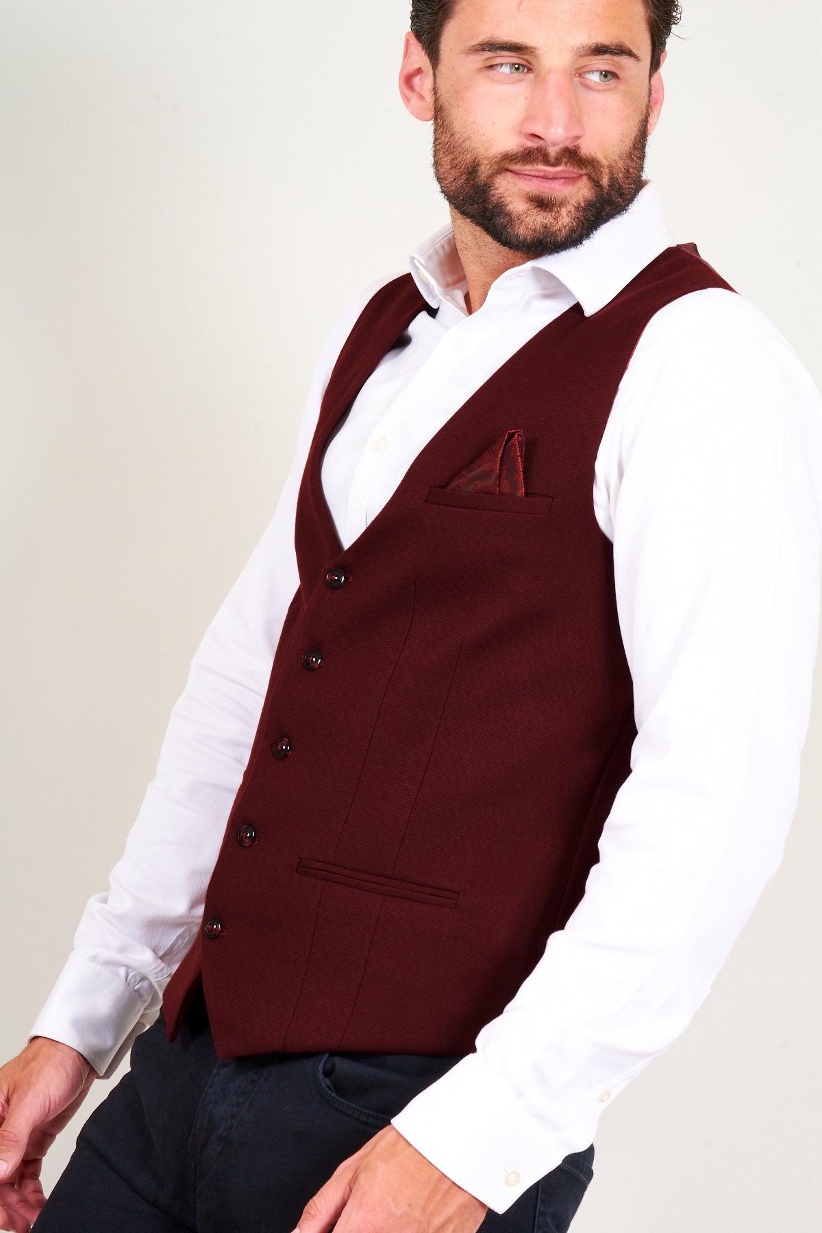 A bearded man wears a slim fit white dress shirt and the marcdarcy KELLY - Wine Single Breasted Waistcoat with a matching pocket square, looking to the side against a plain light background.