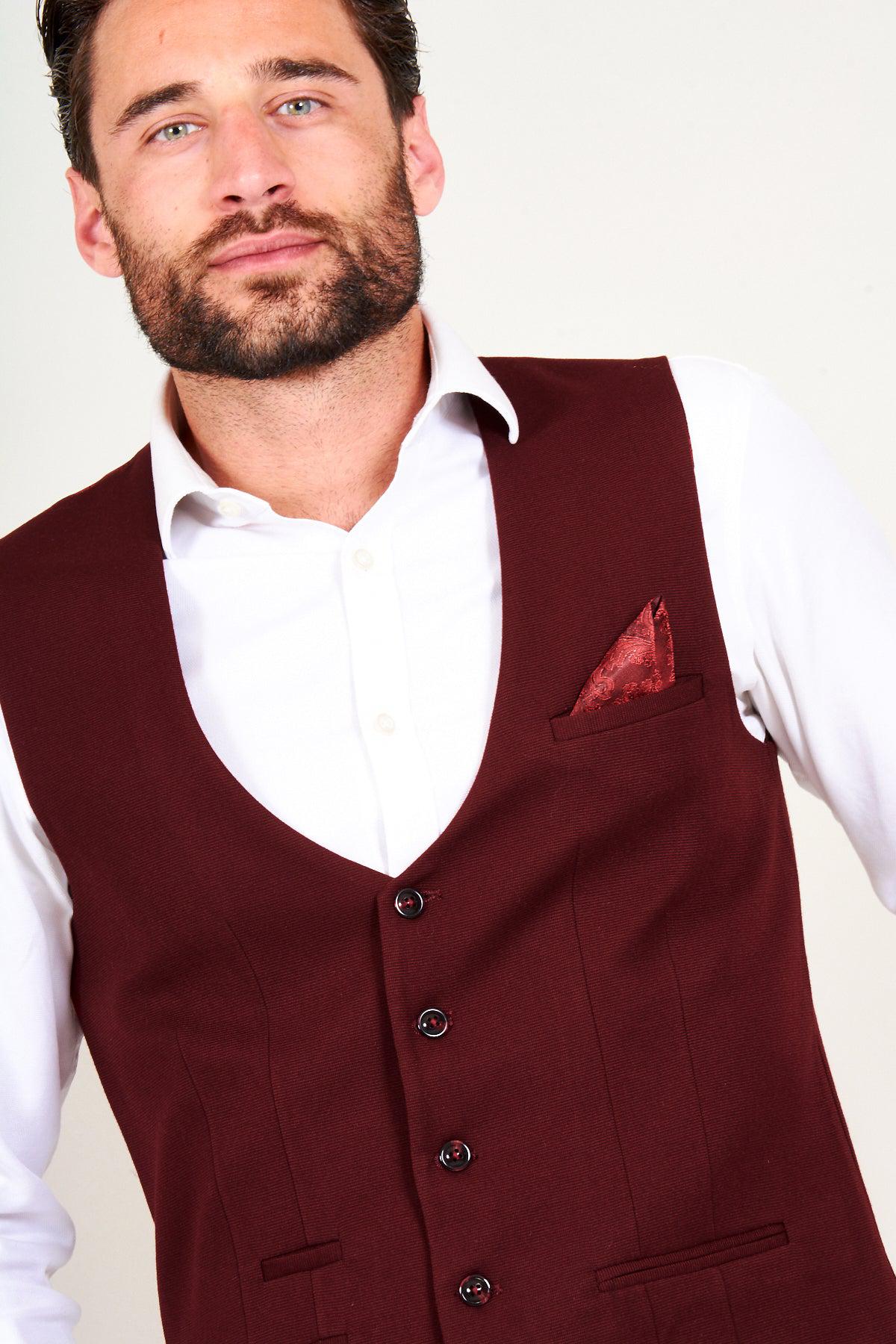 A man wears the marcdarcy KELLY Wine Single Breasted Waistcoat over a white shirt, with a red patterned pocket square visible in the vest pocket.