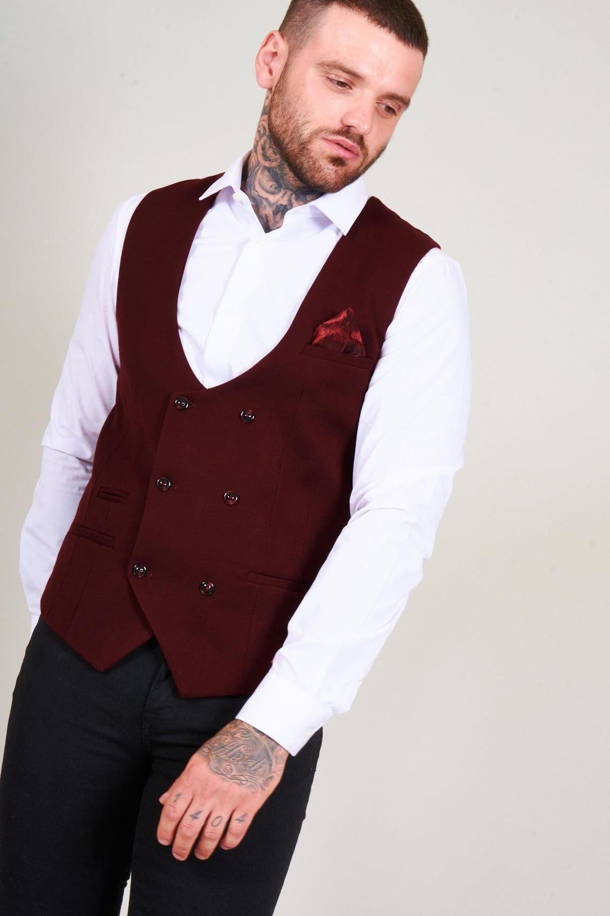 A man wears the marcdarcy KELLY Wine Double Breasted Waistcoat over a white shirt and black trousers, finished with a patterned pocket square.