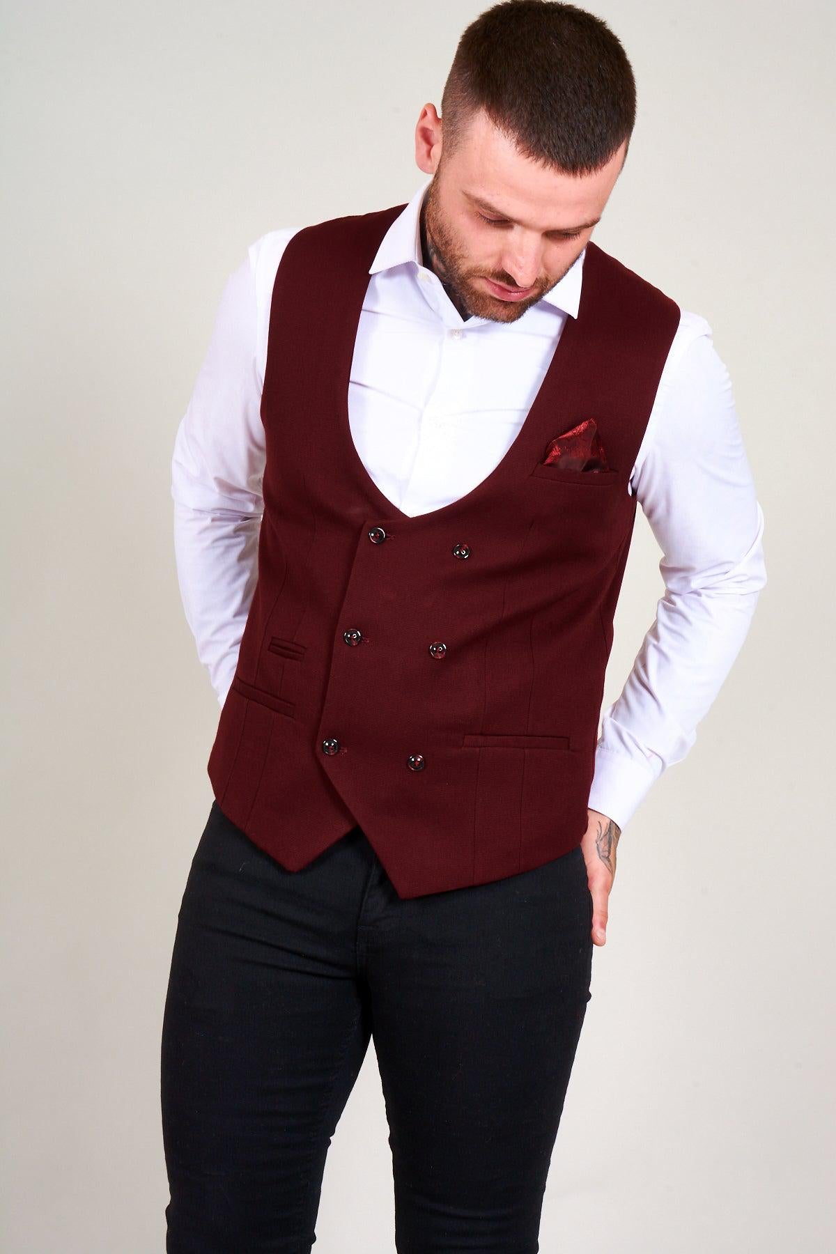 A man wears the marcdarcy KELLY Wine Double Breasted Waistcoat over a white shirt and black pants, with his hands in his pockets.