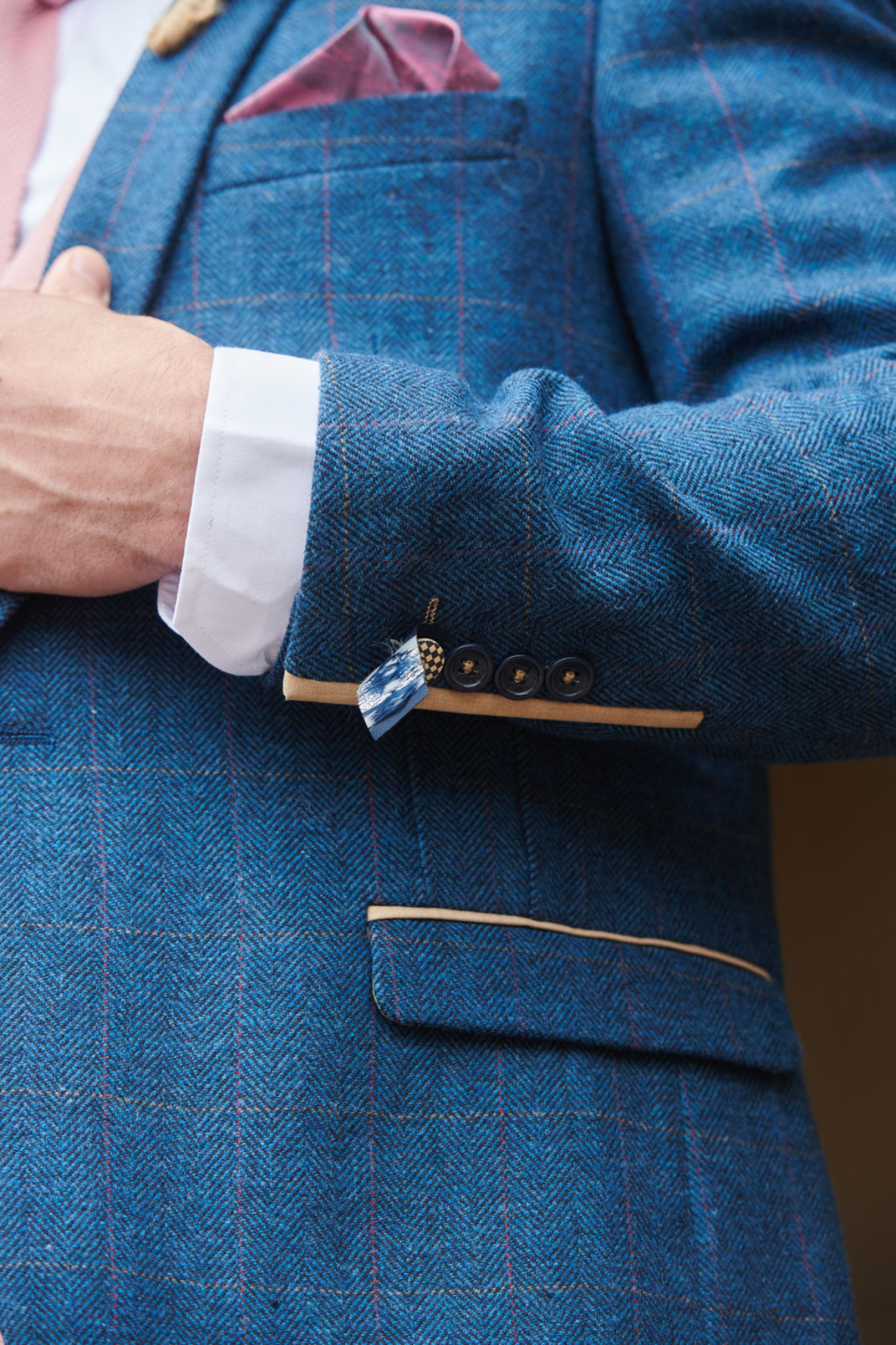 A man wears the marcdarcy DION blue tweed check suit with a Kelvin pink waistcoat, pink pocket square, and blue checkered lapel pin—perfect for creating standout mix-and-match wedding looks.