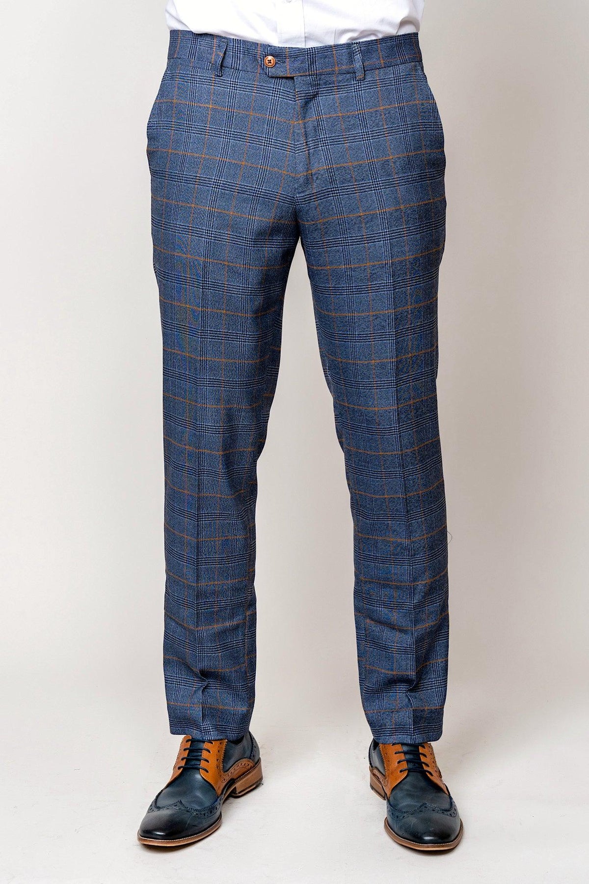 A person in marcdarcy’s JENSON Sky Blue Check Suit with Kelvin Tan Waistcoat, white shirt, and two-tone brown and navy oxfords stands against a plain light backdrop, showcasing sophisticated mix-and-match style.