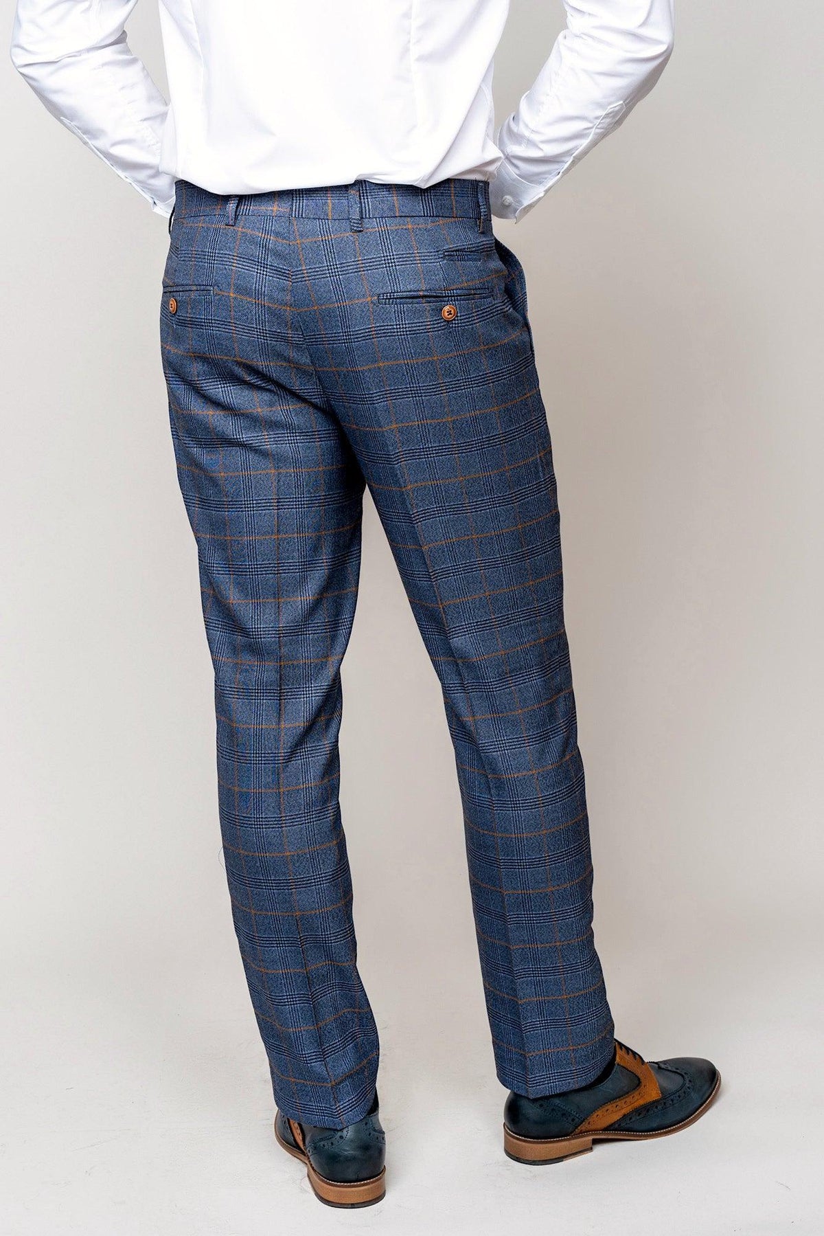 A person models the marcdarcy JENSON Sky Blue Check Suit paired with a Kelvin Tan Waistcoat, styled with brown and blue dress shoes, hands in pockets, viewed from the back against a plain light background.