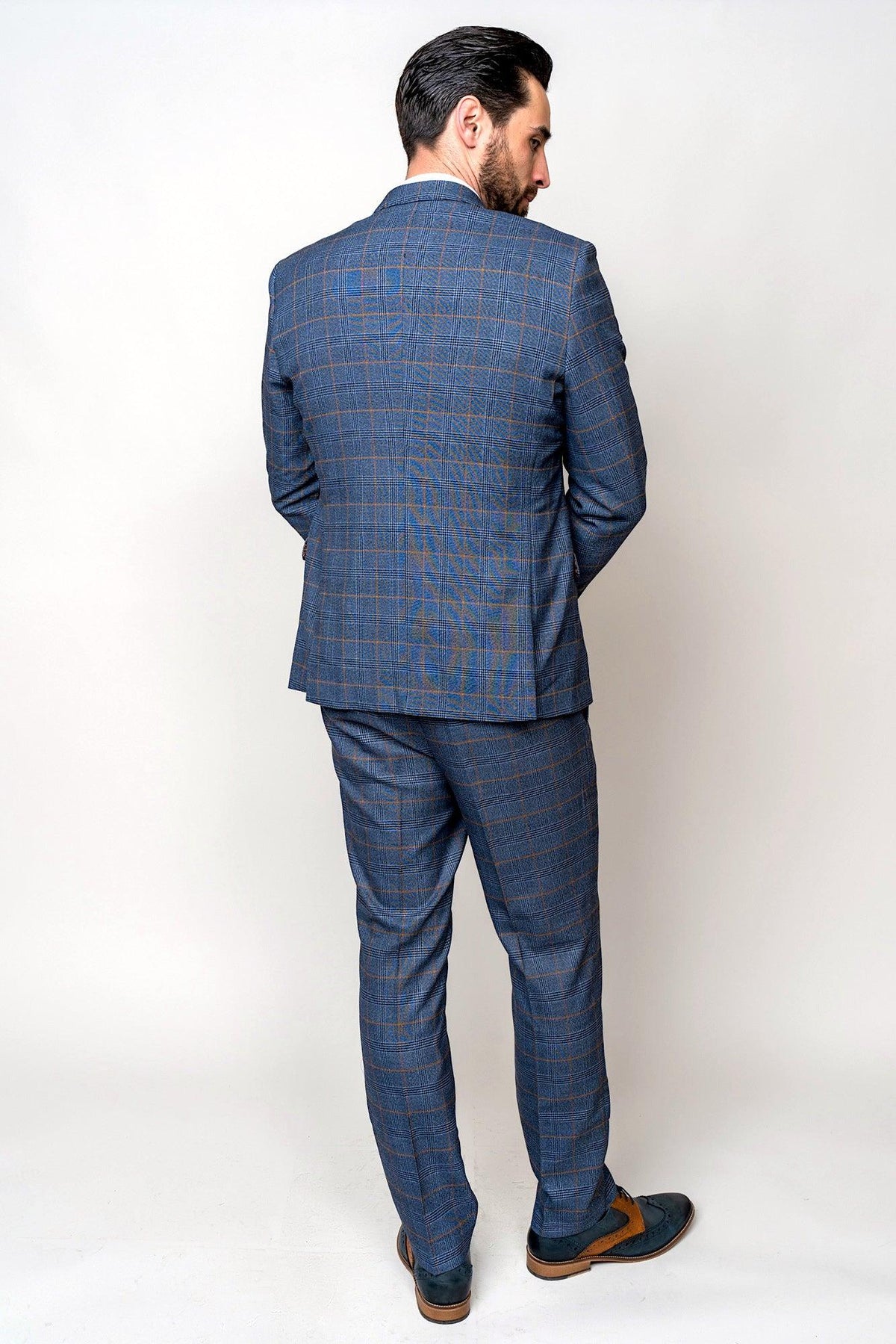 A man with dark hair and a beard stands with his back to the camera, wearing a marcdarcy JENSON Sky Blue Check Suit paired with a Kelvin Tan Waistcoat, against a plain white background.