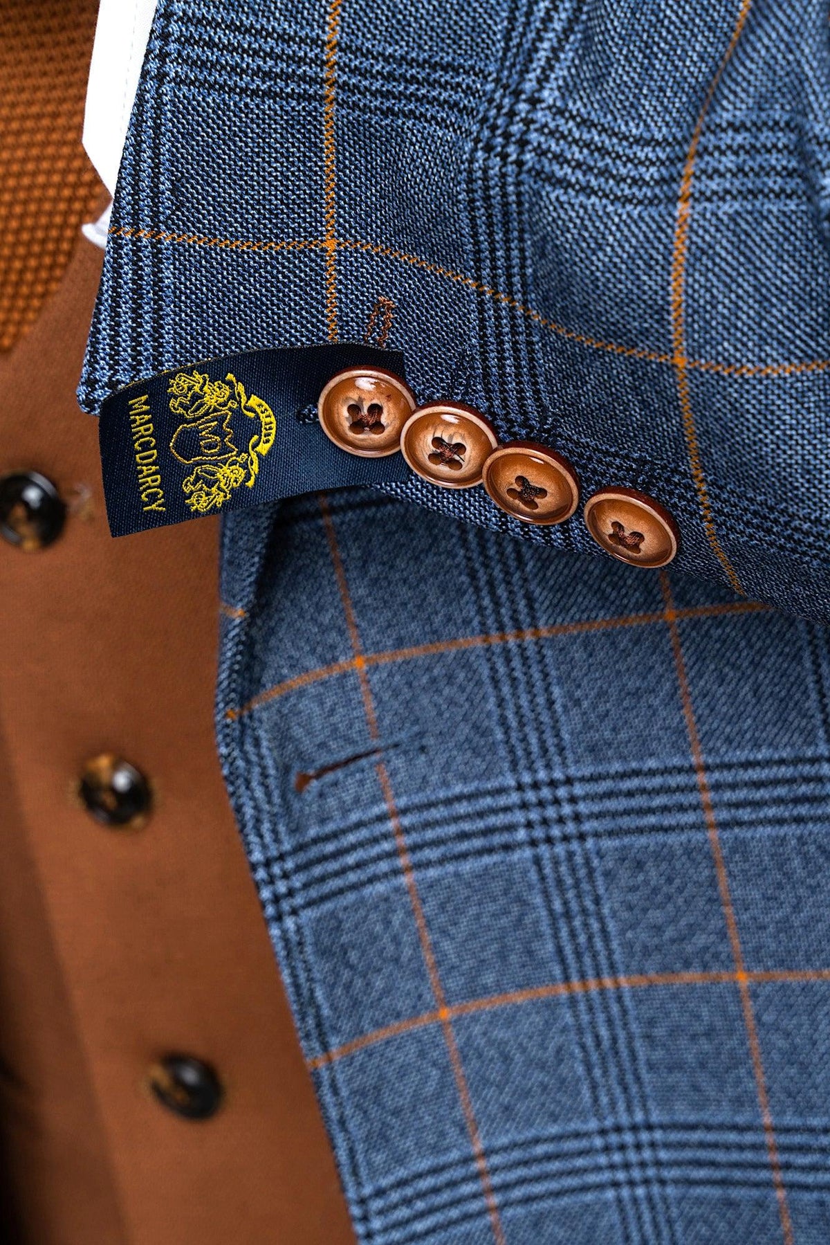 Close-up of a marcdarcy JENSON Sky Blue Check Suit jacket sleeve with brown buttons and navy label, worn over a Kelvin Tan double-breasted waistcoat with black buttons.