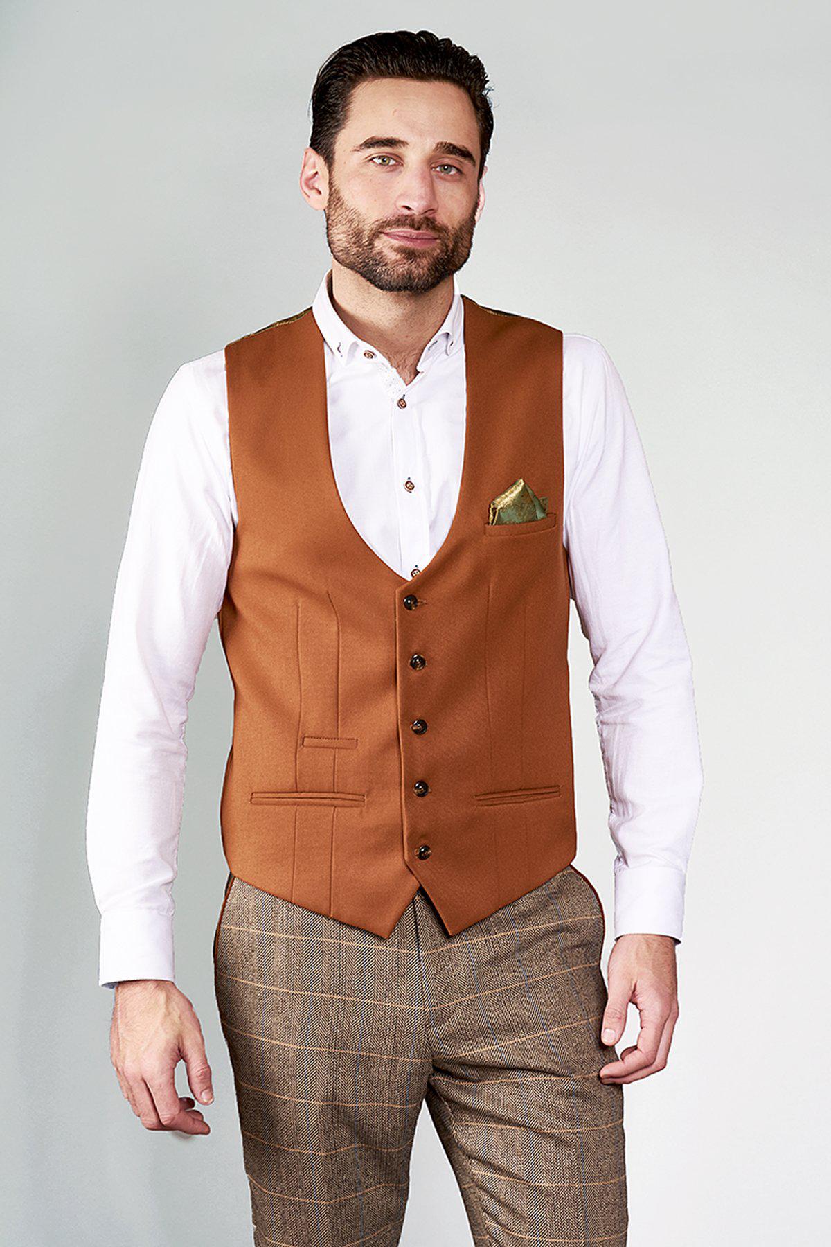 A man with short dark hair and a beard wears a slim fit white shirt, brown plaid trousers, and the marcdarcy KELLY Dark Tan Single Breasted Waistcoat, standing against a plain light background.