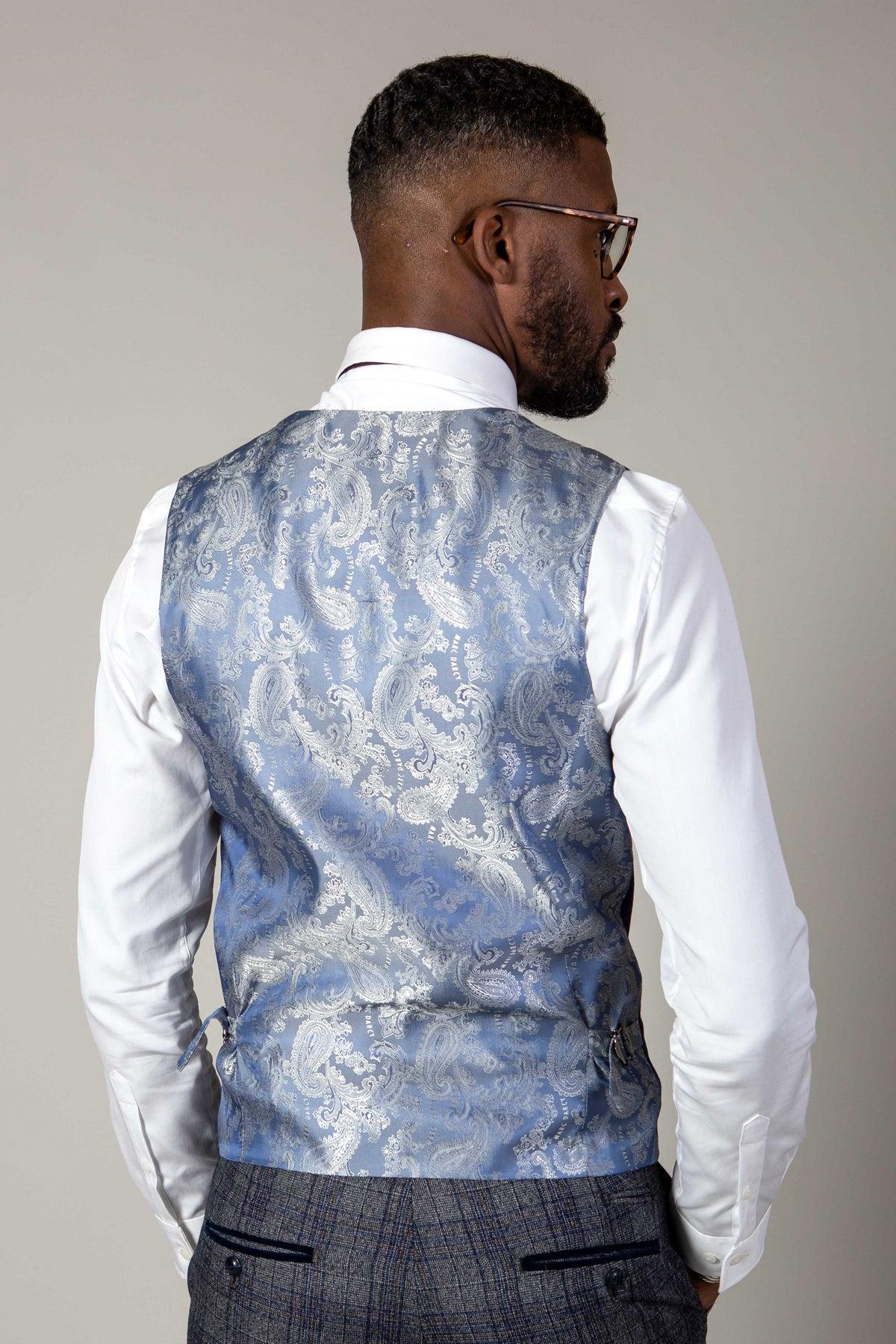 A man in glasses and a white shirt is seen from behind, showcasing the marcdarcy KELVIN Royal Blue Single Breasted Waistcoat with paisley patterns and grey plaid trousers against a plain background.