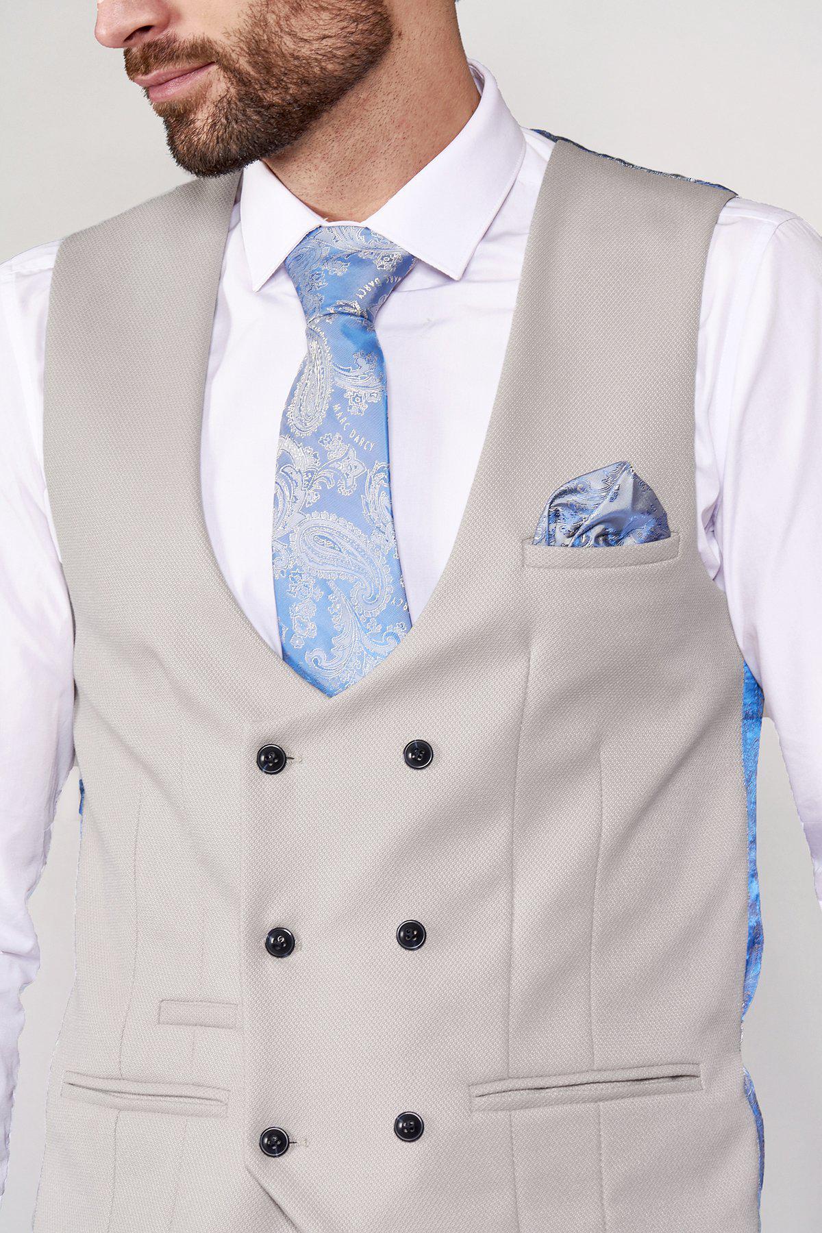 A man wears the marcdarcy DION Blue Tweed Check Suit with a Kelvin Stone Waistcoat over a white shirt, styled with a blue paisley tie and matching pocket square—an elegant groom suit, his head slightly turned and face partly visible.