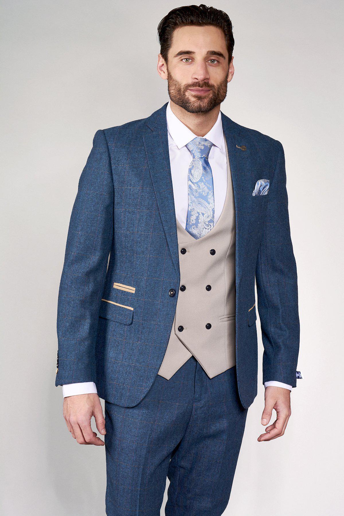 A man wears the marcdarcy DION blue tweed check suit with a Kelvin Stone waistcoat, white shirt, and light blue paisley tie.