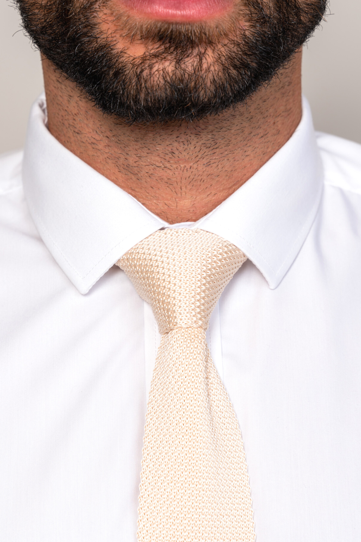 Close-up of a bearded man wearing a white dress shirt and the Accessory KT - Cream Knitted Tie, highlighting a refined, textured wedding look.
