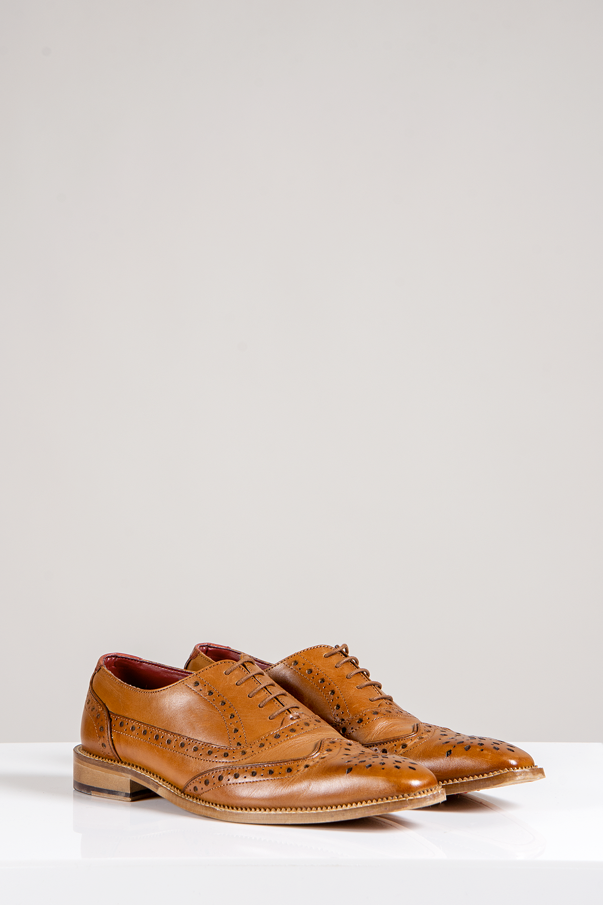 The Marc Darcy LARKIN Mid Tan Leather Brogue Shoes, crafted from full grain leather with decorative perforations, are displayed on a white surface against a neutral background.