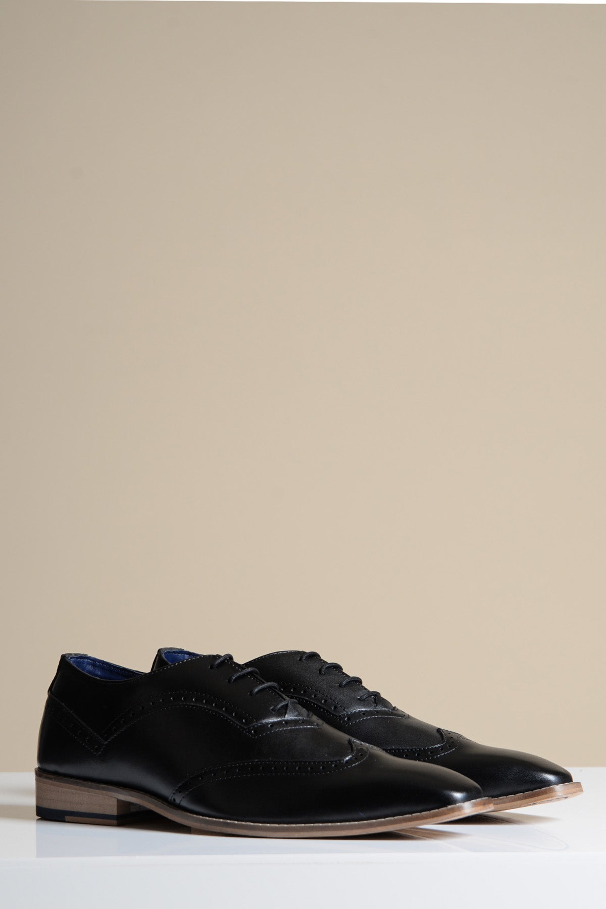 The Marc Darcy DAWSON Black Wingtip Oxford Brogue Shoe features full grain leather, decorative stitching, and laces, displayed on a white surface with a plain beige background.