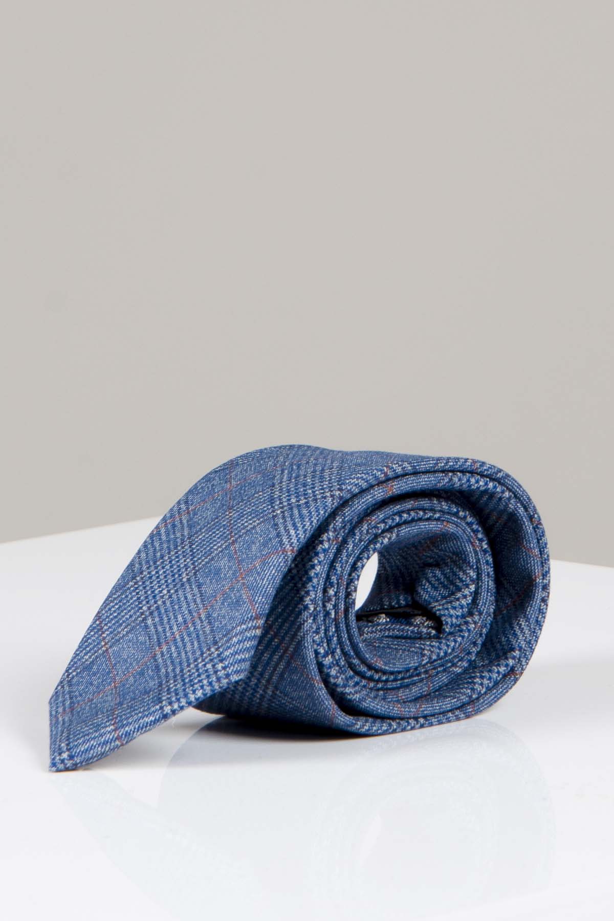 The GEORGE - Light Blue Check Tie by Accessory is rolled up and displayed on a white reflective surface with a plain light gray background.