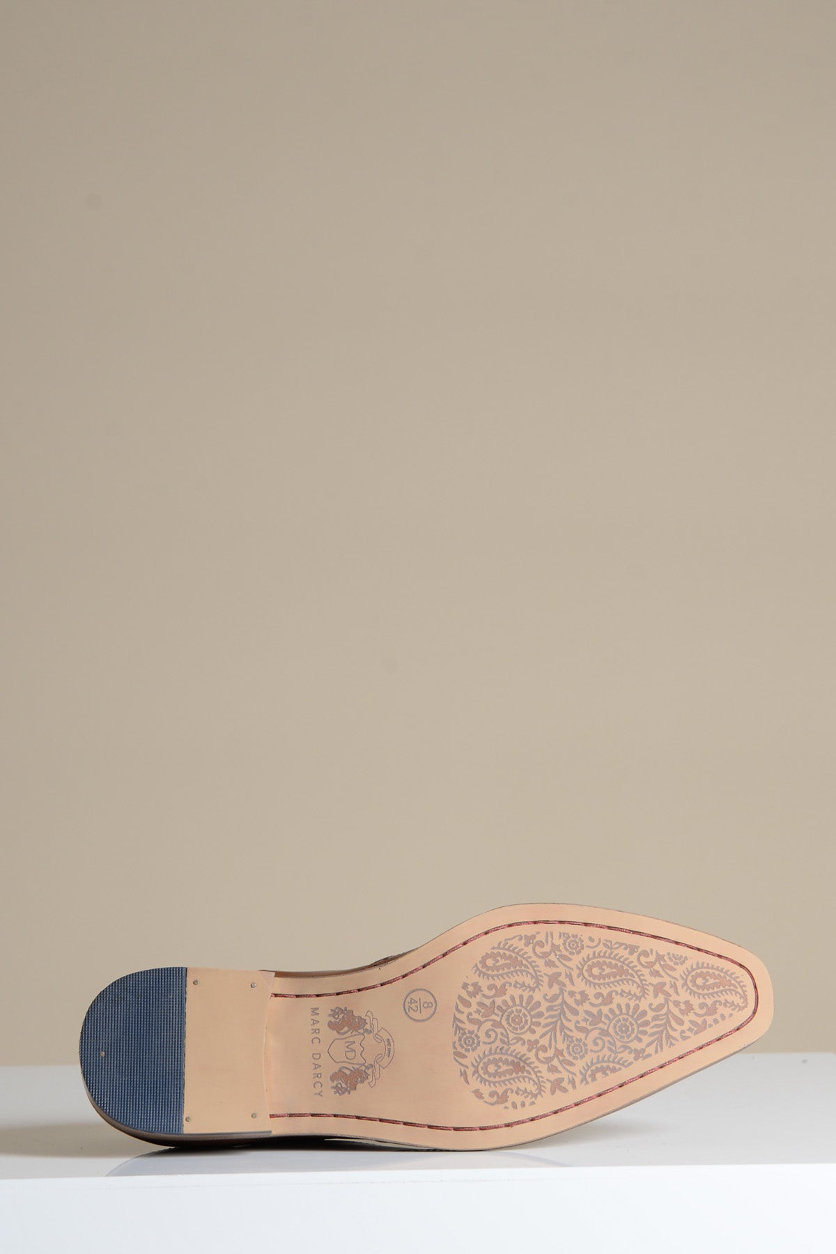 The DAWSON Tan Wingtip Oxford Brogue Shoe by Marc Darcy is shown on its side, revealing a tan leather sole with a detailed floral pattern and small logo near the arch, set against a plain beige background.