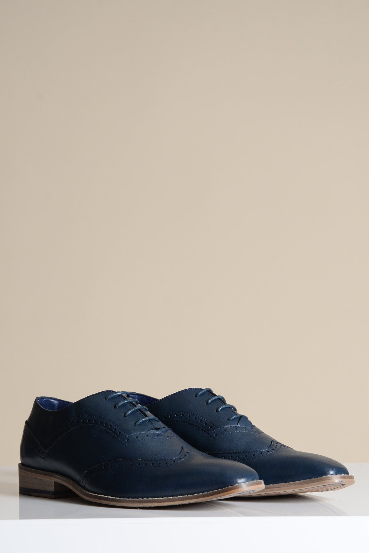 The Marc Darcy DAWSON Navy Wingtip Oxford Brogue Shoe, crafted from full grain leather with detailed broguing and matching laces, is displayed on a white surface against a plain beige background.