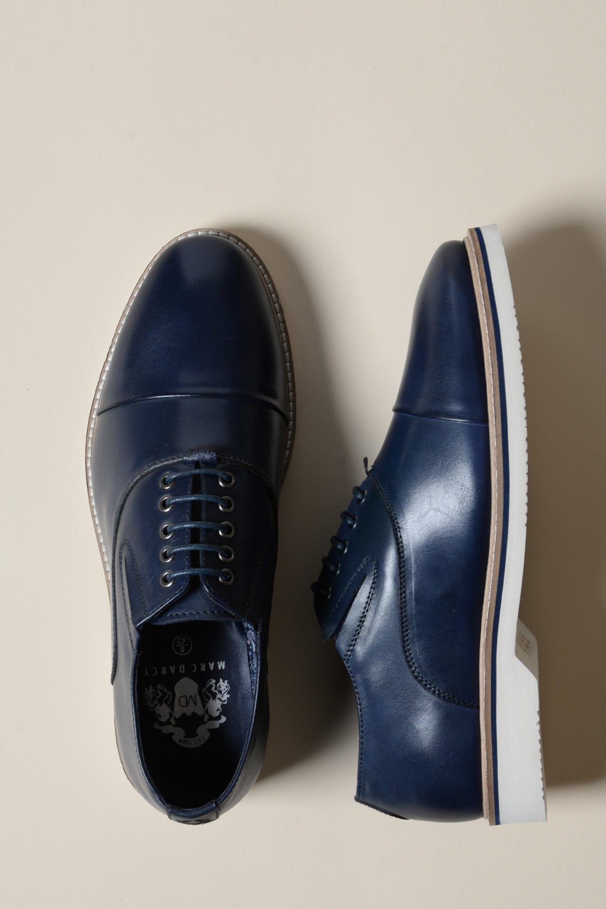 The GAVIN Navy Blue Leather Cap Toe Oxford Shoe by Marc Darcy features full grain leather, white soles, and a lace-up closure. Shown from a top-down view on a plain background—ideal elegant footwear for refined occasions.