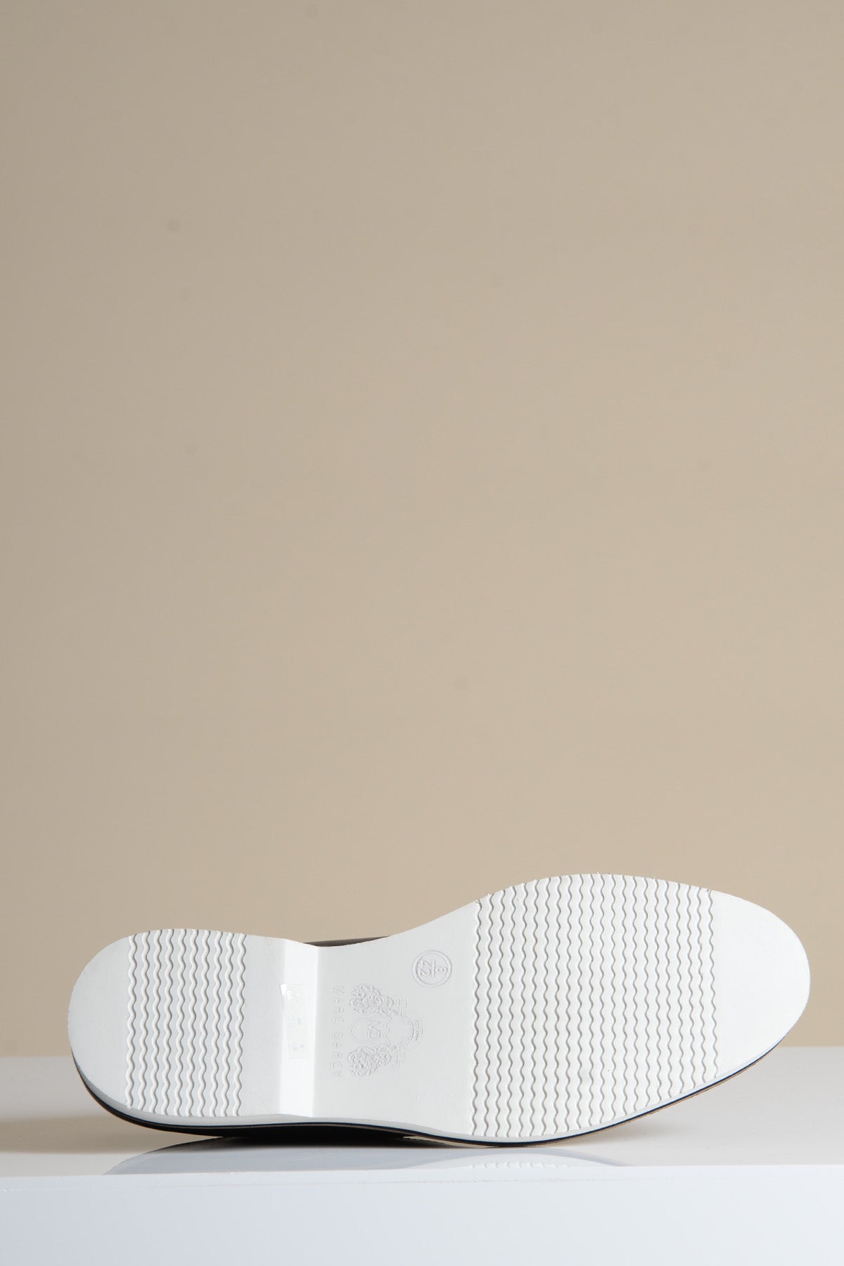 The sole of the Marc Darcy GAVIN Black Leather Cap Toe Oxford Shoe is shown against a neutral background, featuring wavy tread patterns, a round logo, and text.
